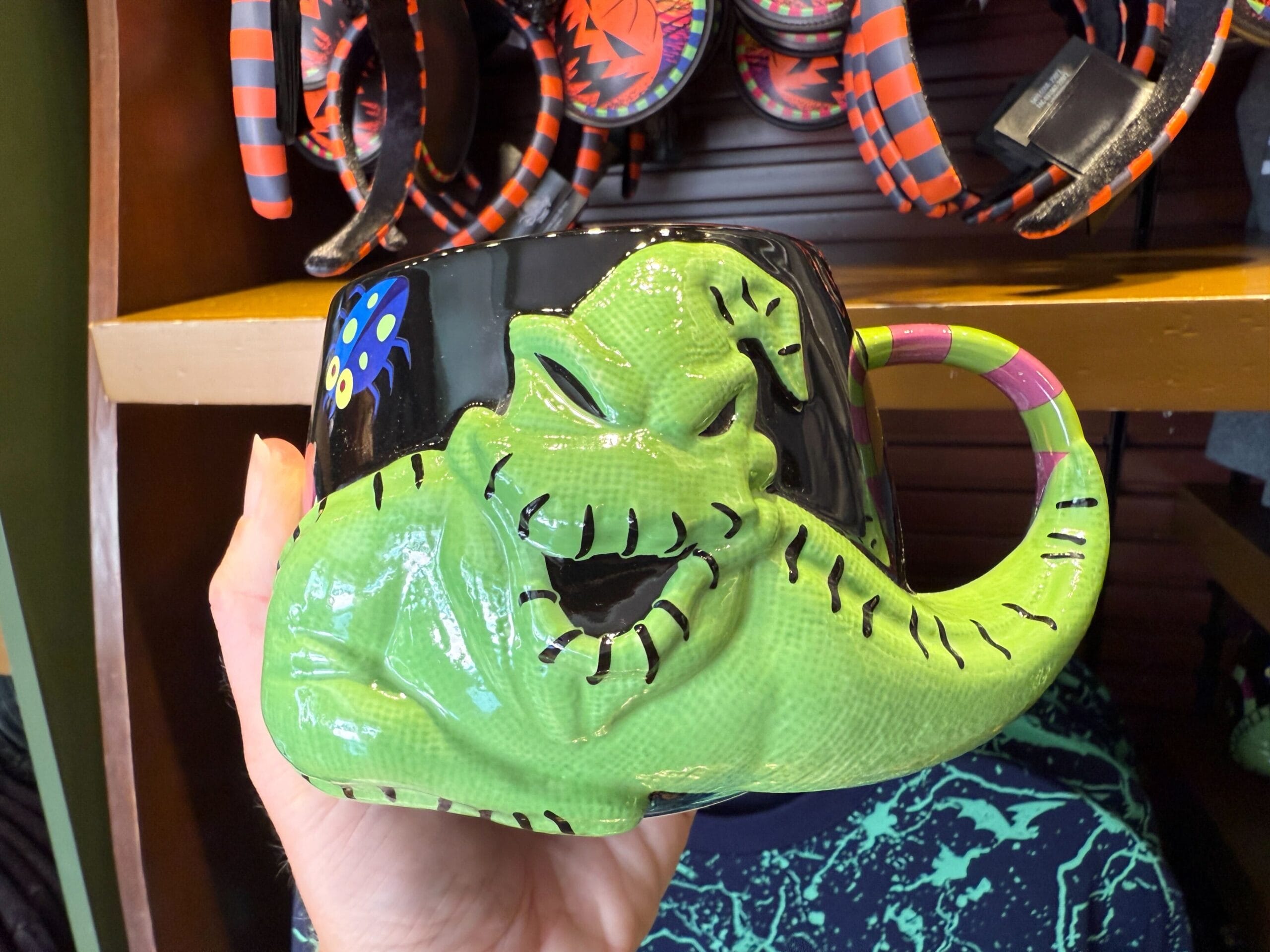 A hand holds a quirky piece of The Nightmare Before Christmas merchandise: an Oogie Boogie-shaped mug.