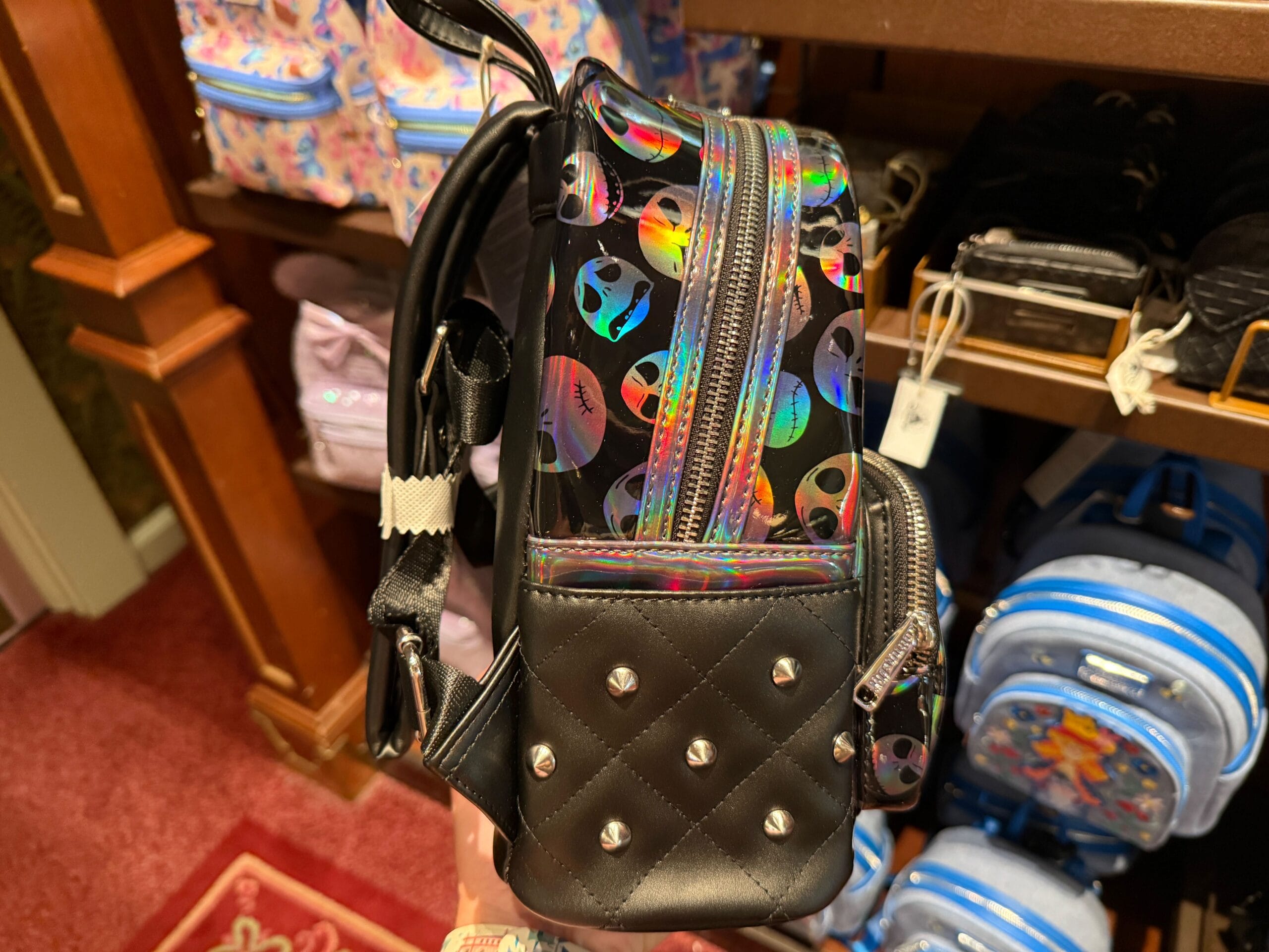 A small black backpack with silver studs and a holographic pattern, perfect merchandise for The Nightmare Before Christmas fans.