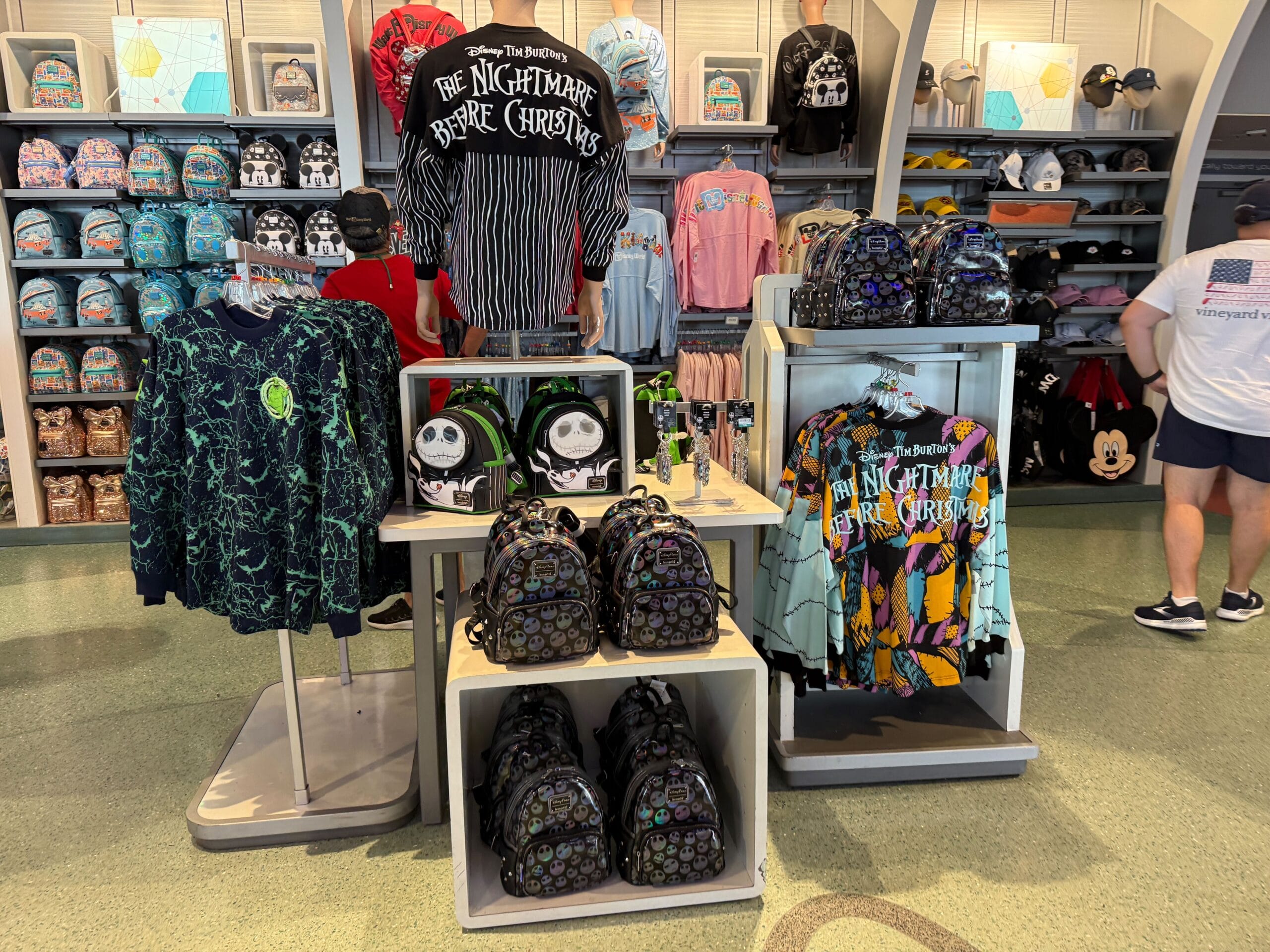 Display of The Nightmare Before Christmas merchandise, featuring themed bags, shirts, and backpacks in a store.