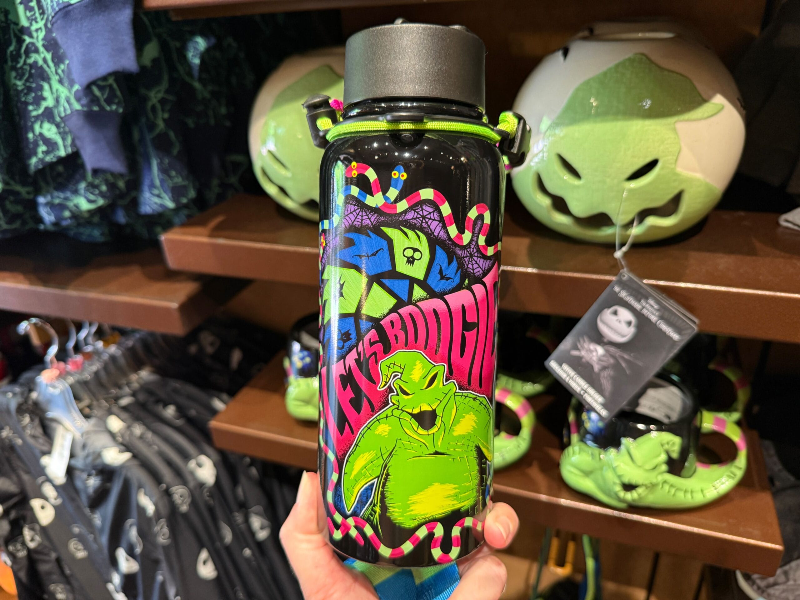 A hand holds colorful The Nightmare Before Christmas merchandise featuring Oogie Boogie in a store display.