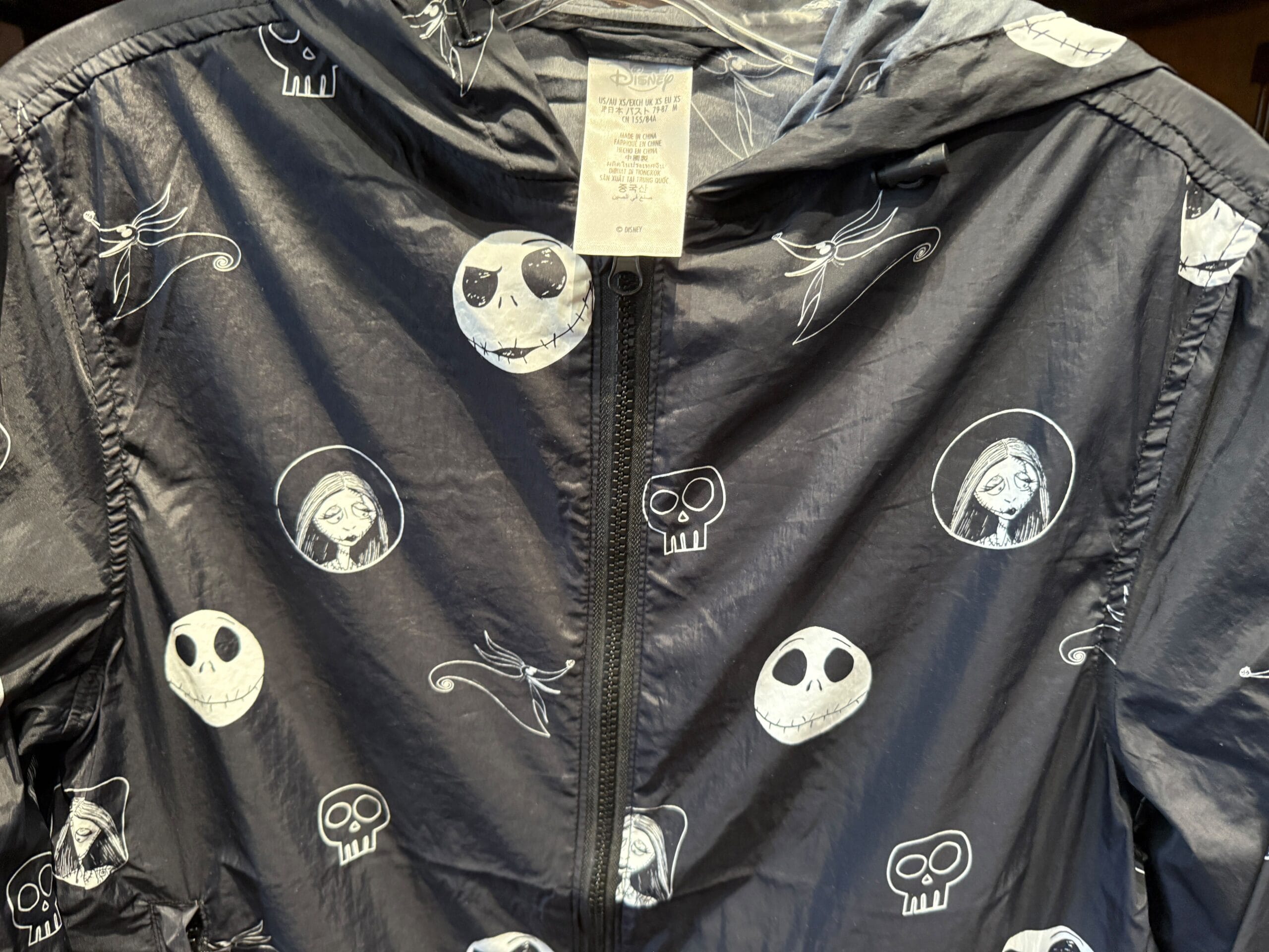 Close-up of a black jacket with white skulls and floral designs, perfect Nightmare Before Christmas merchandise.