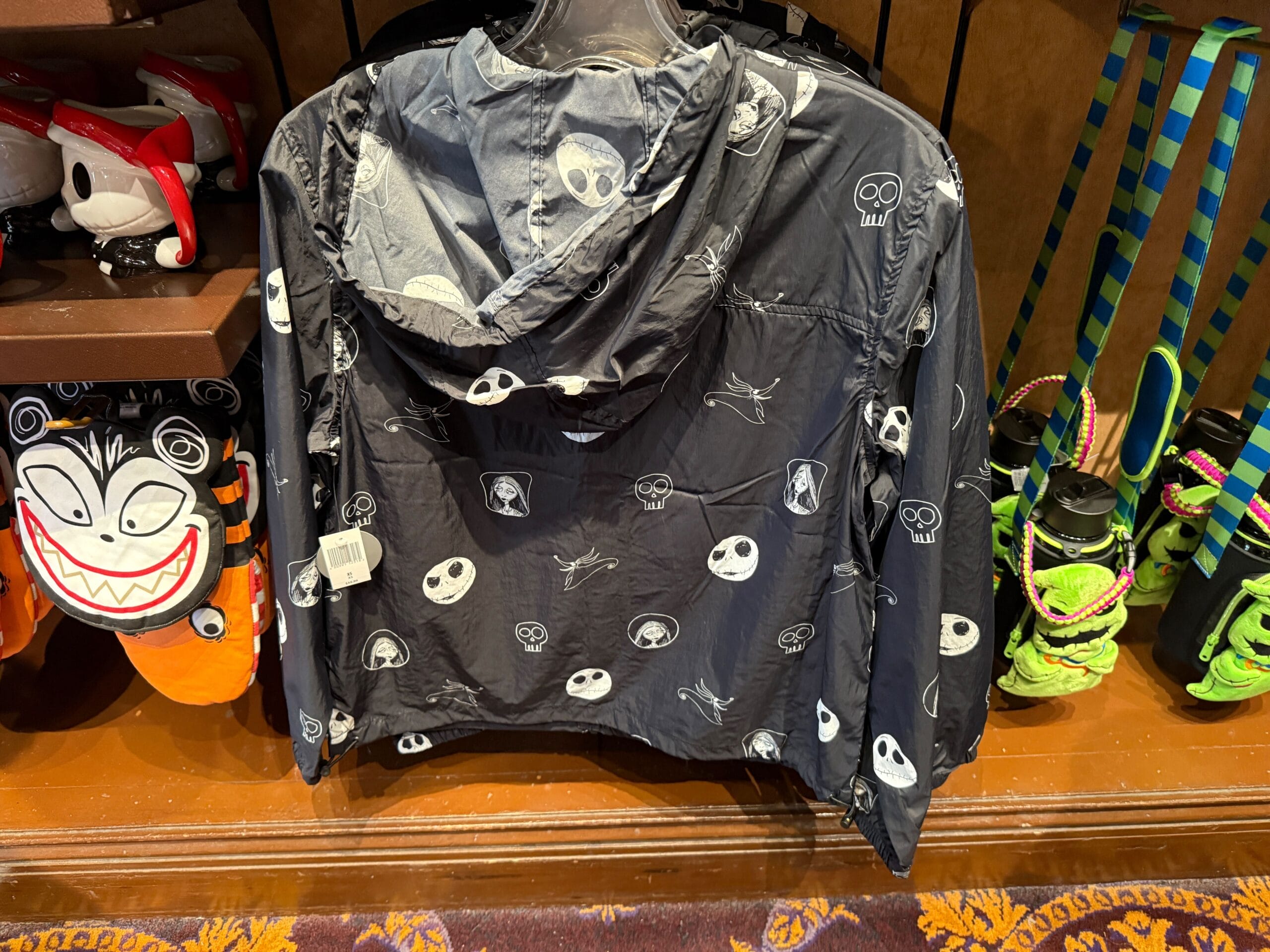 A black jacket featuring white Jack Skellington faces, perfect Nightmare Before Christmas merchandise on display in a store.