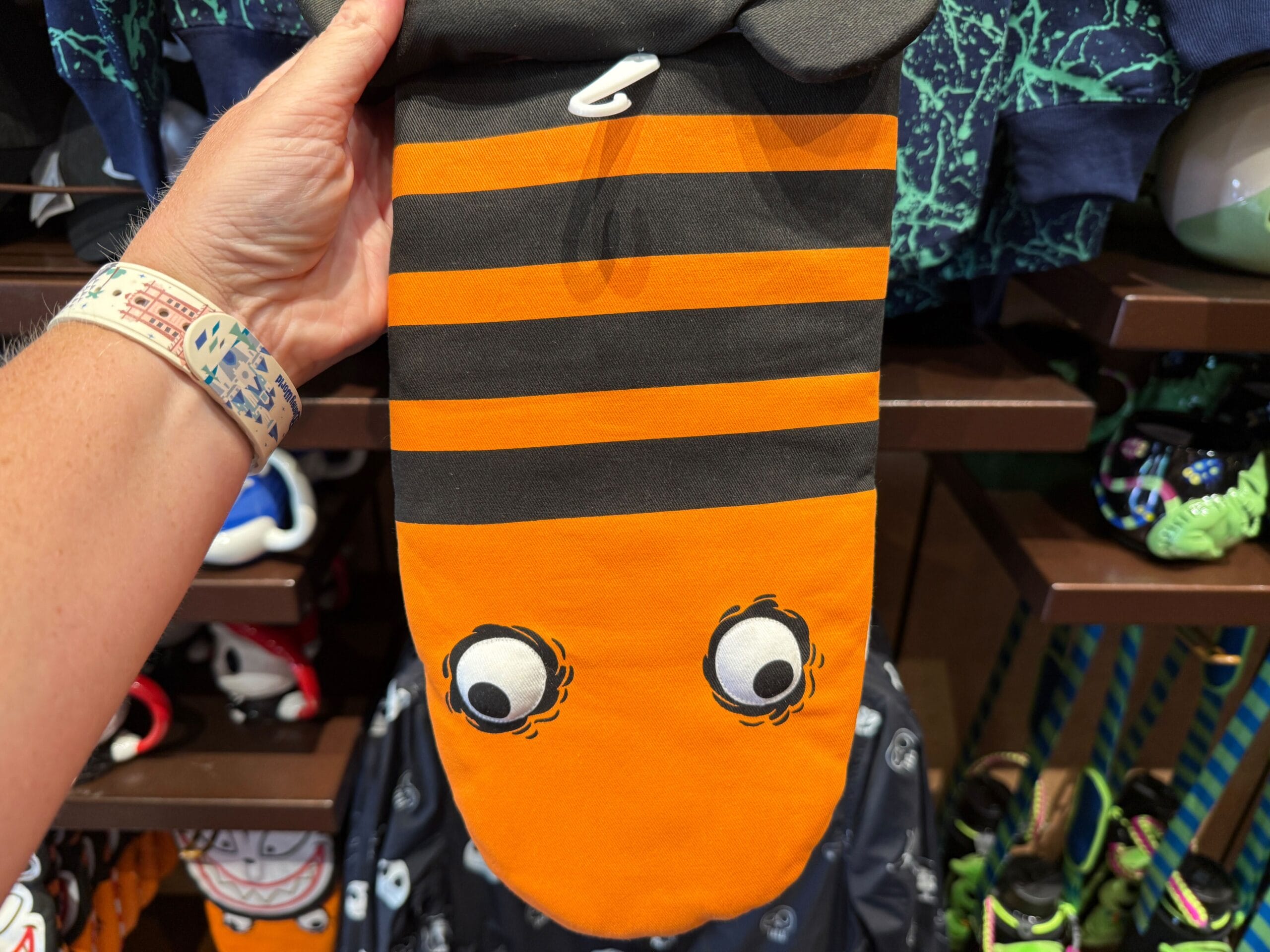 A hand holds quirky merchandise—a striped item with cartoon eyes, evoking The Nightmare Before Christmas whimsy.