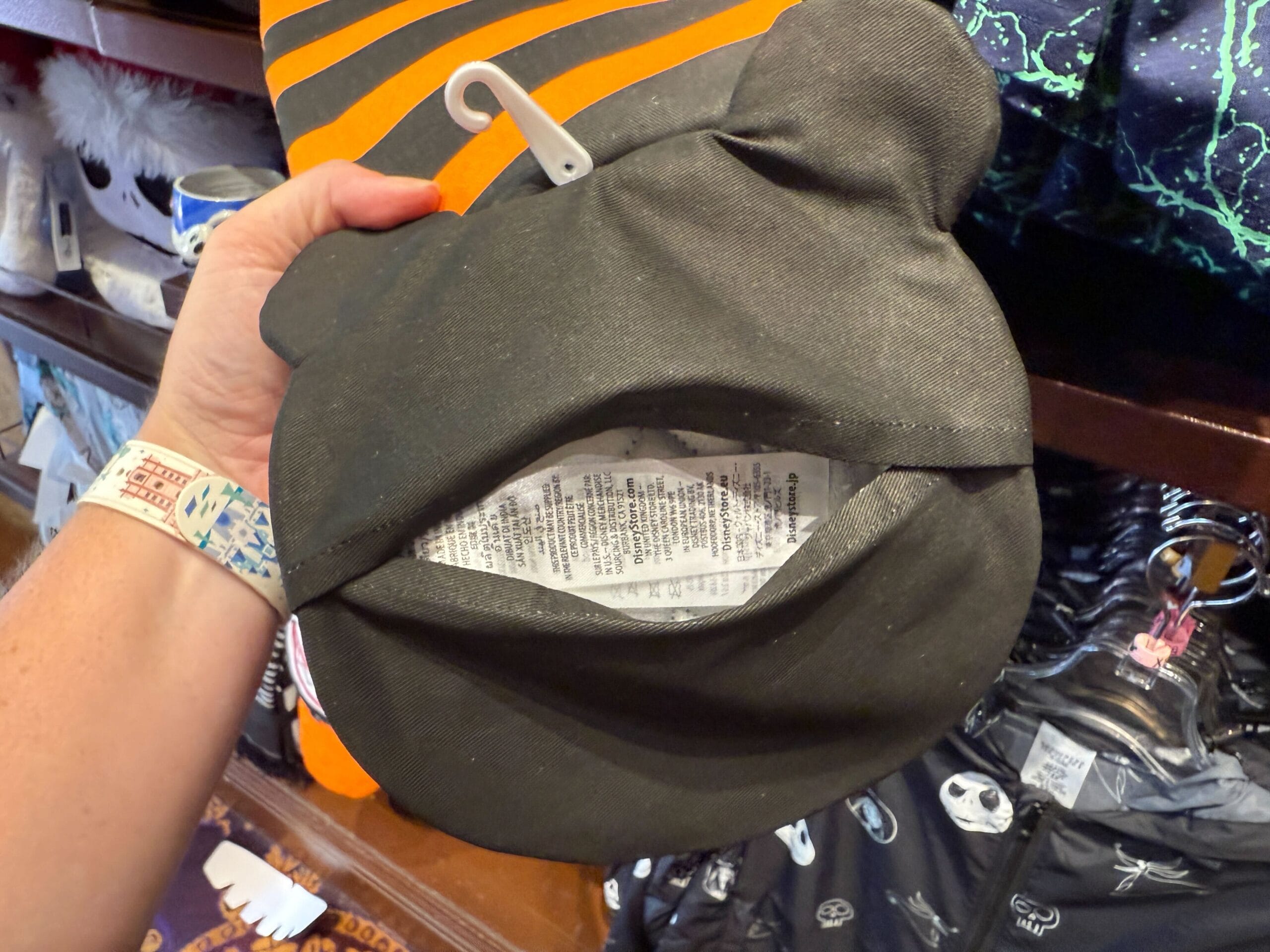 A hand holds The Nightmare Before Christmas Merchandise plush, revealing a white tag with printed information inside.