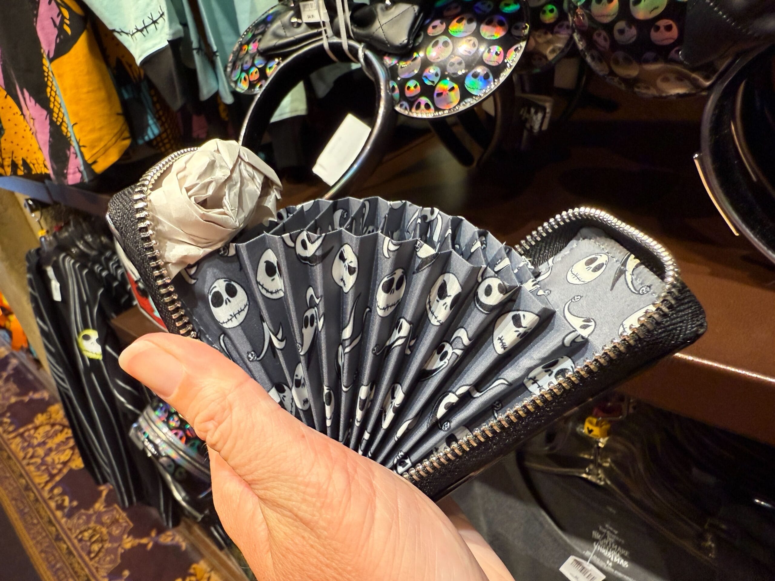 A hand holds merchandise: an accordion-style wallet featuring Jack Skellington from The Nightmare Before Christmas.