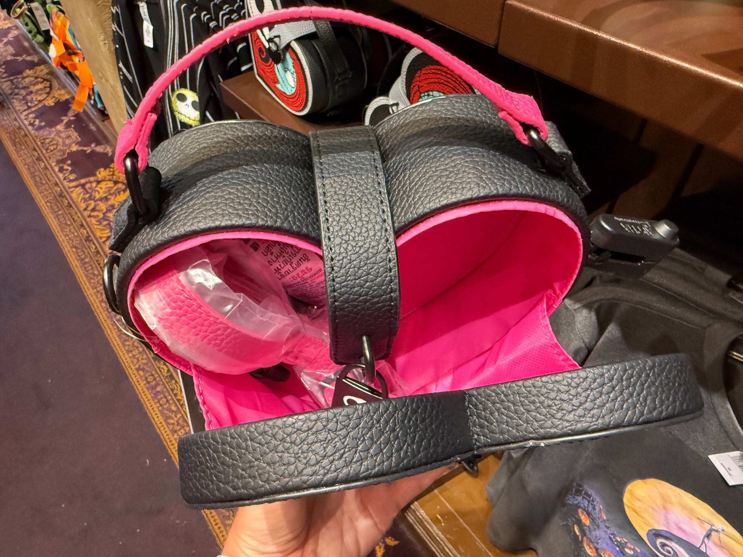 Black and pink heart-shaped Nightmare Before Christmas handbag with a top handle, showing its bright pink interior.