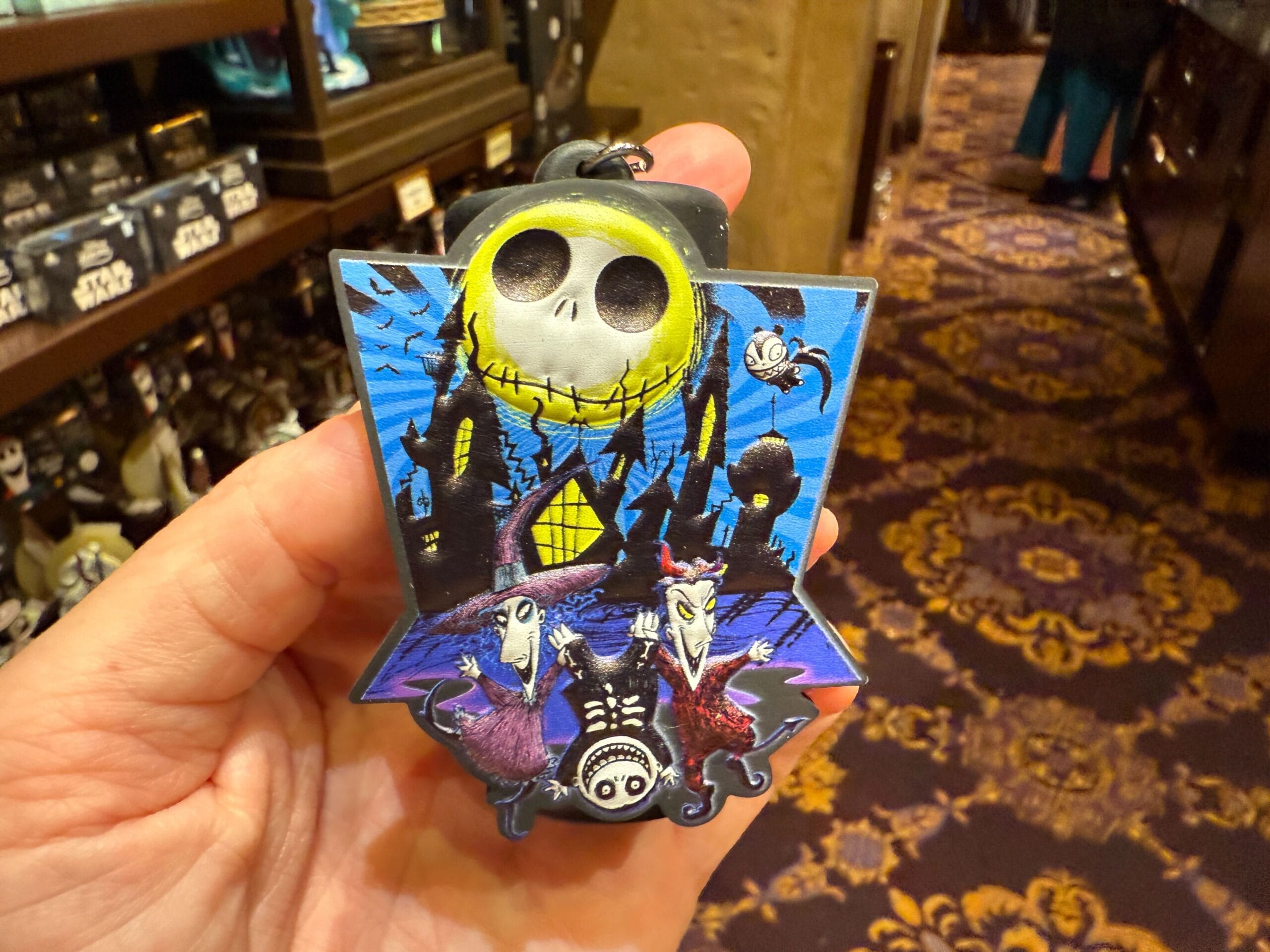 A hand holds new Nightmare Before Christmas merchandise: an ornament with Jack Skellington and other characters.
