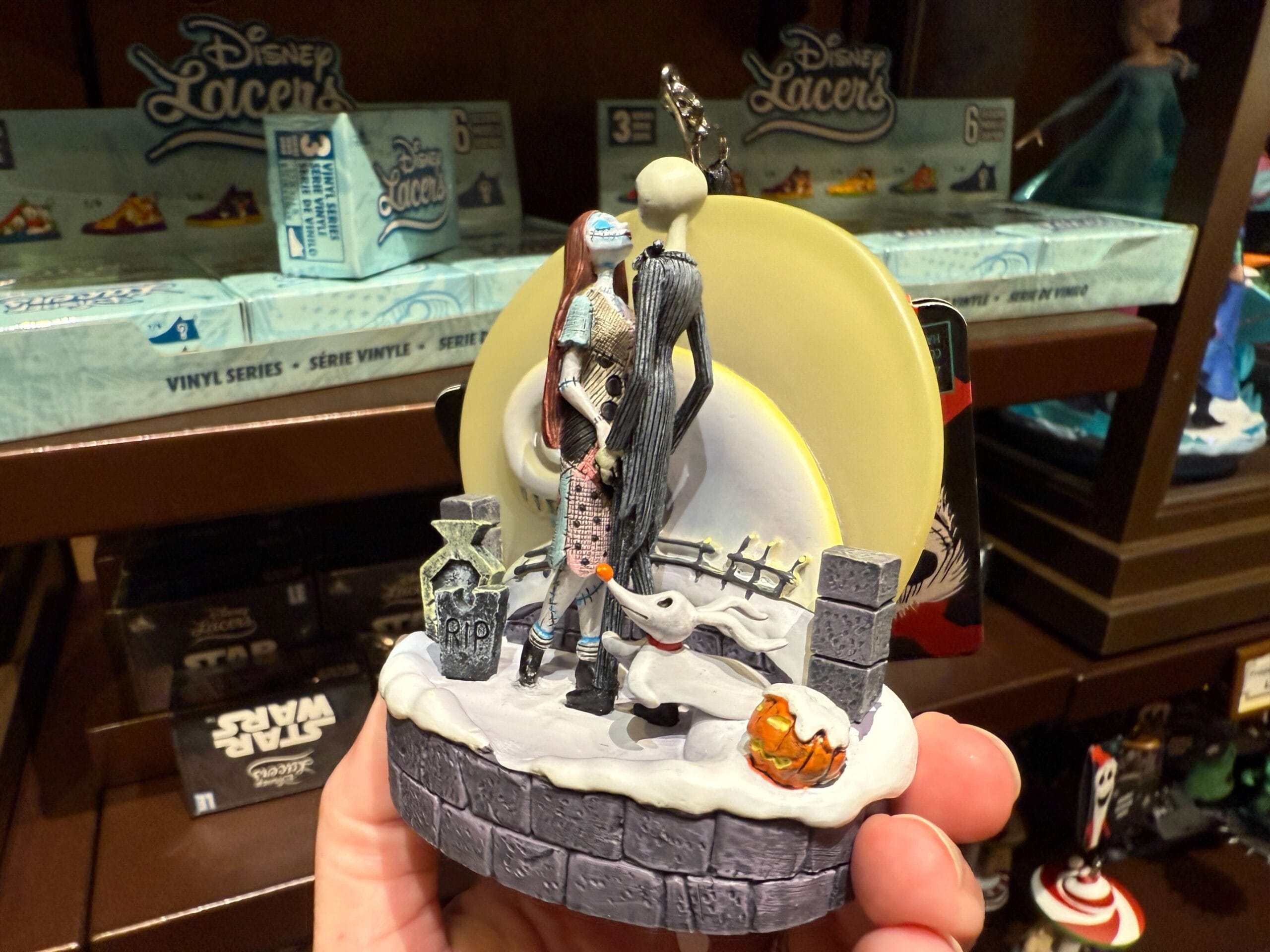Hand holding new Nightmare Before Christmas merchandise: Jack and Sally ornament on a snowy base.