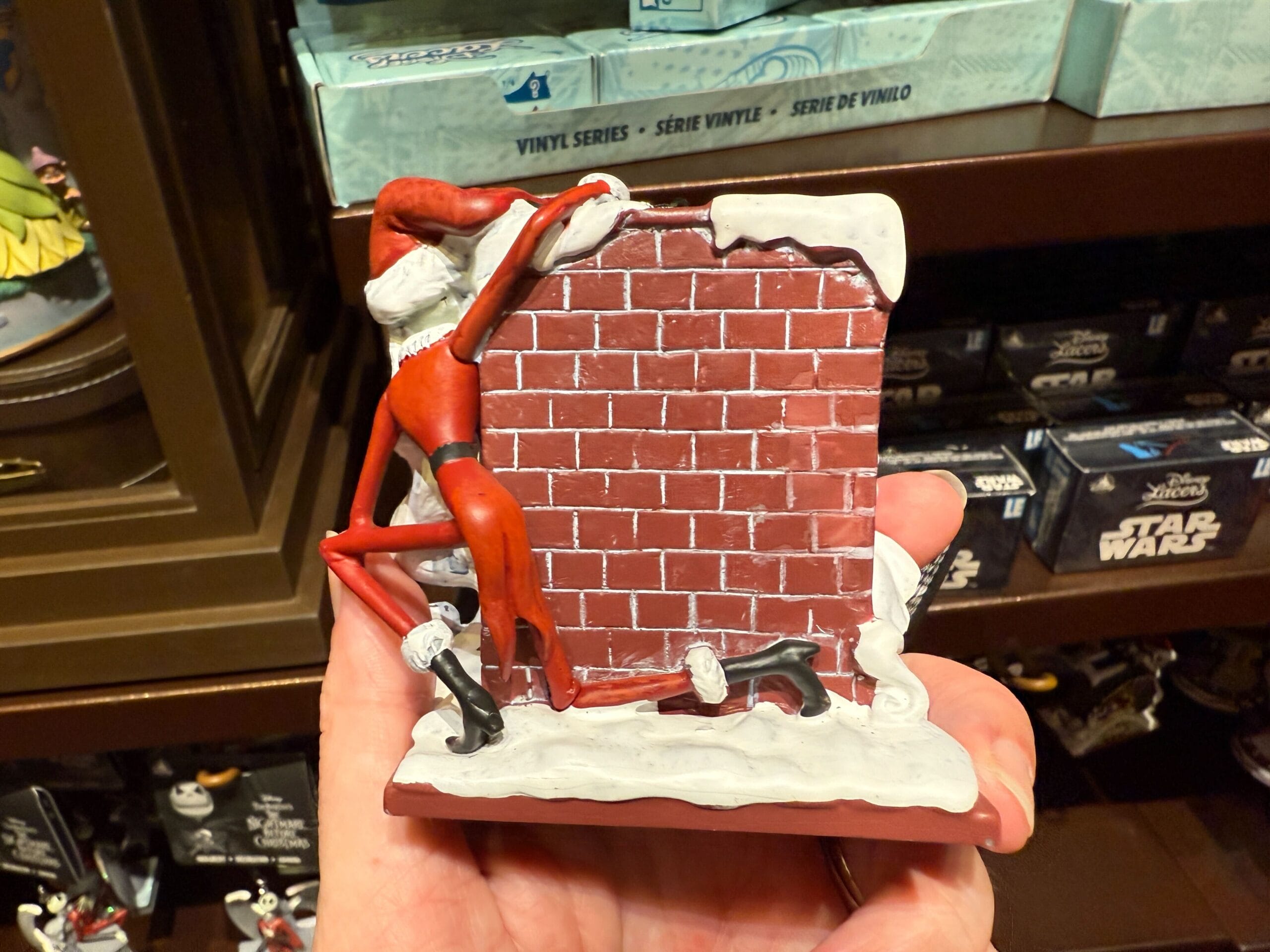 A new Nightmare Before Christmas figurine of Jack Skellington as Santa climbing a snow-covered chimney.