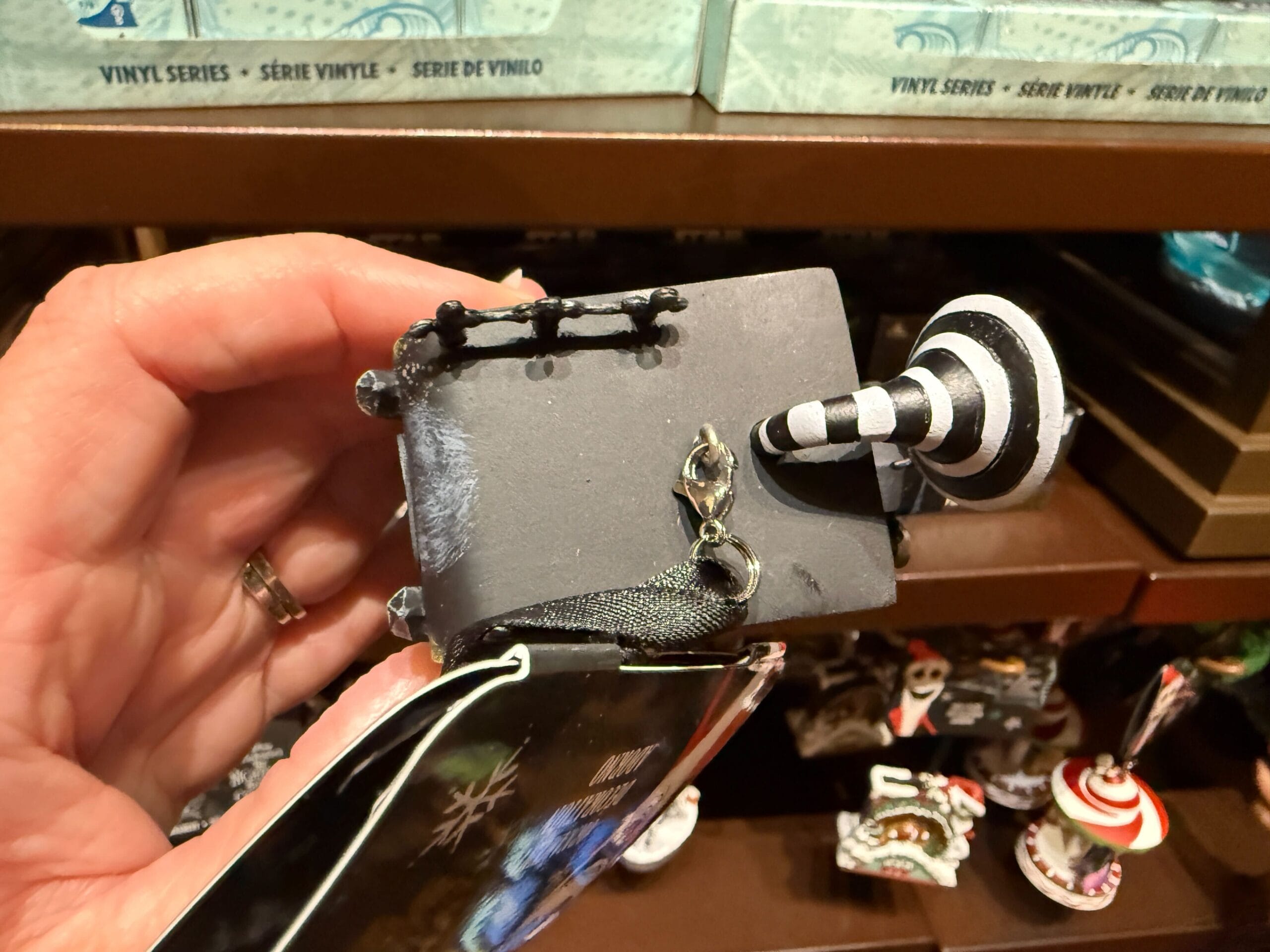 A hand holds new merchandise: a black and white spiral hill ornament from The Nightmare Before Christmas.