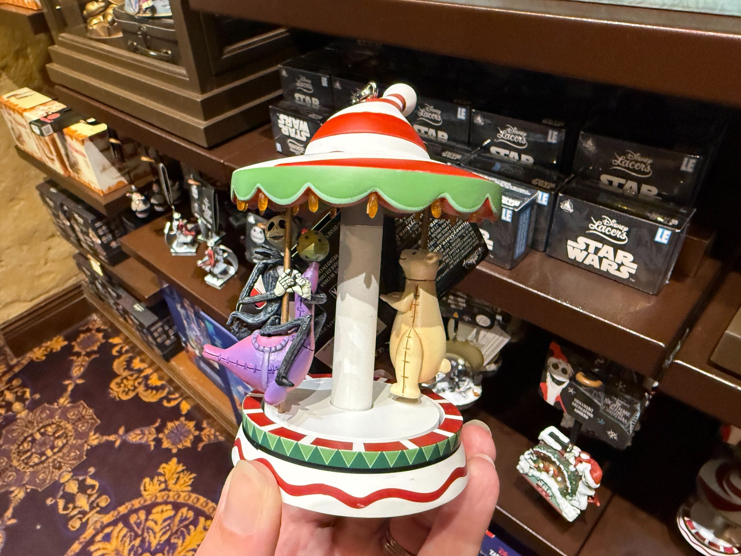 A hand holds Nightmare Before Christmas merchandise in a store, with Star Wars boxes visible on the shelf behind.