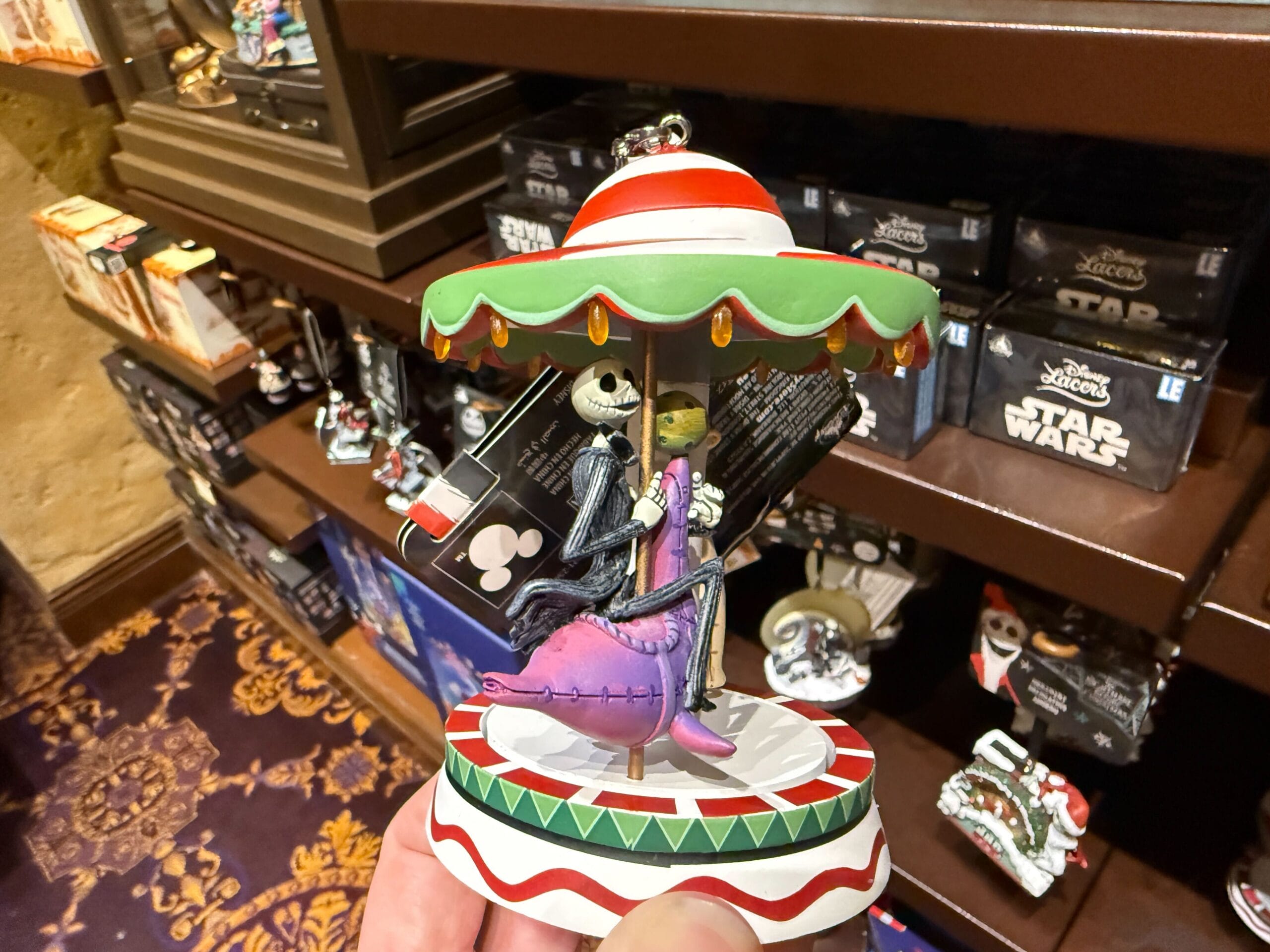 Hand holding The Nightmare Before Christmas merchandise—Jack and Sally figurine under an umbrella in a store.
