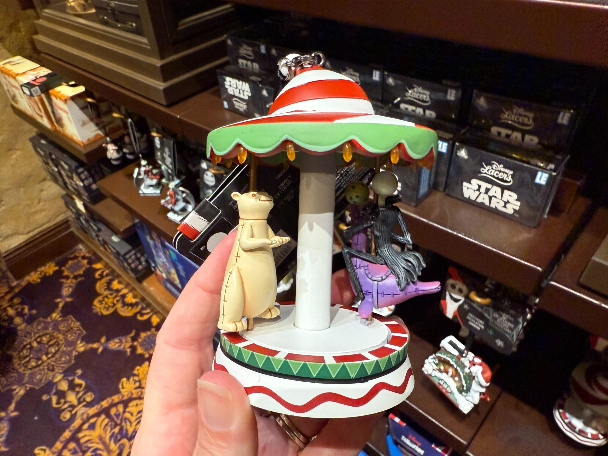 Hand holding a carousel ornament from The Nightmare Before Christmas Merchandise in a store.