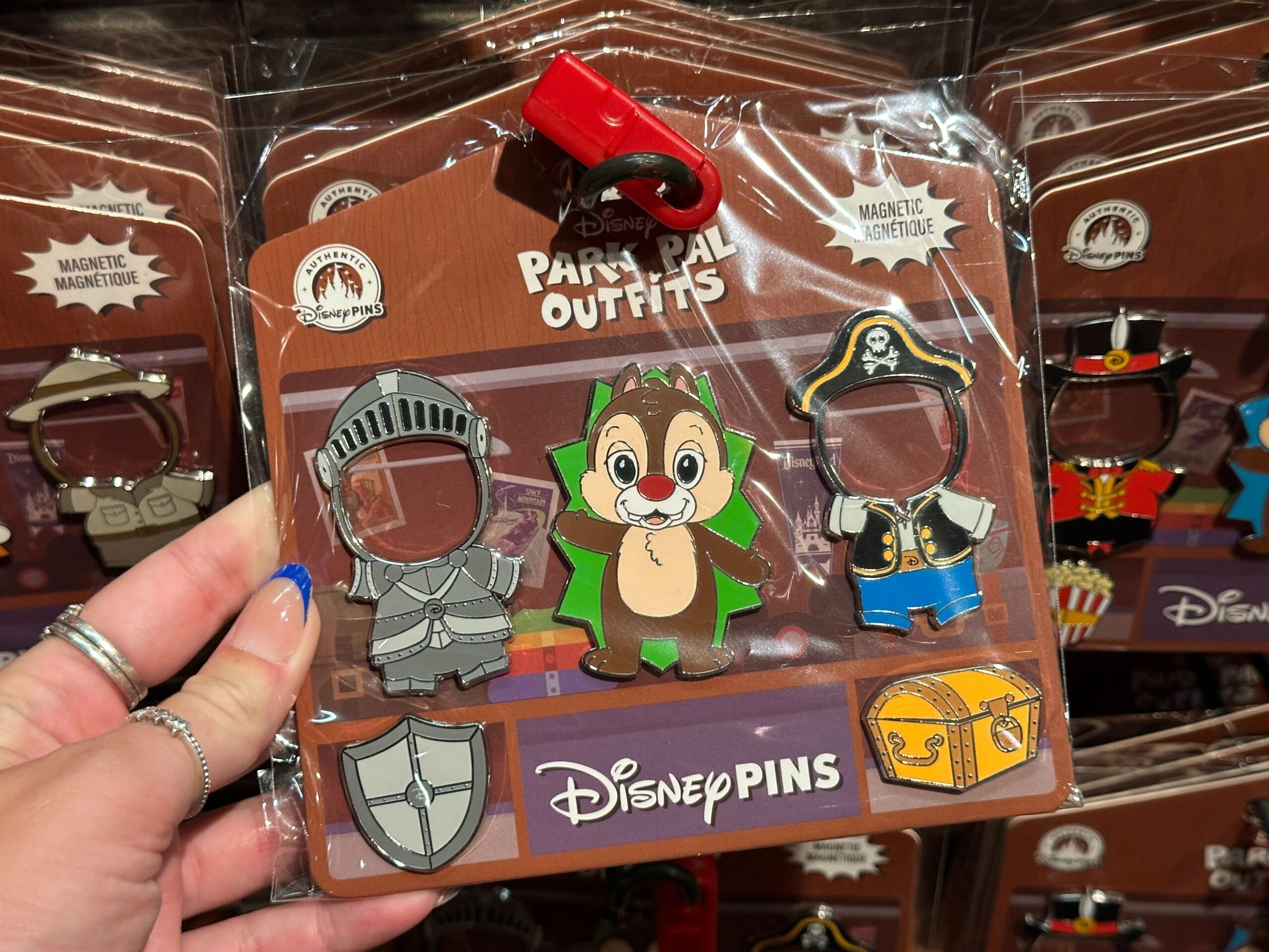 Disney Pins set with a chipmunk and magnetic knight and pirate outfits, displayed in packaging, held by a hand.