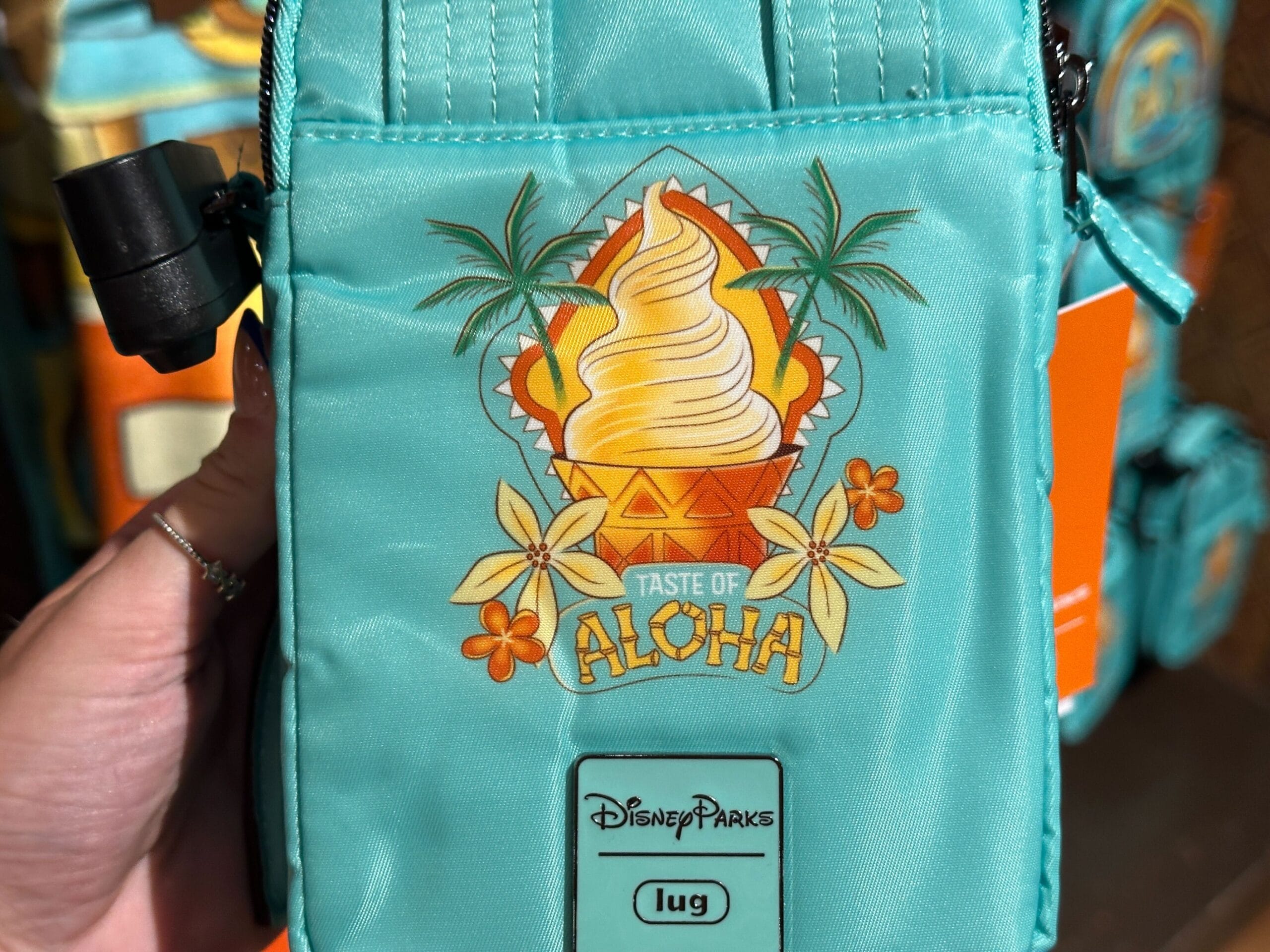 A turquoise Disney Parks bag with a Dole Whip graphic, palm trees, flowers, and text reading "Taste of Aloha.