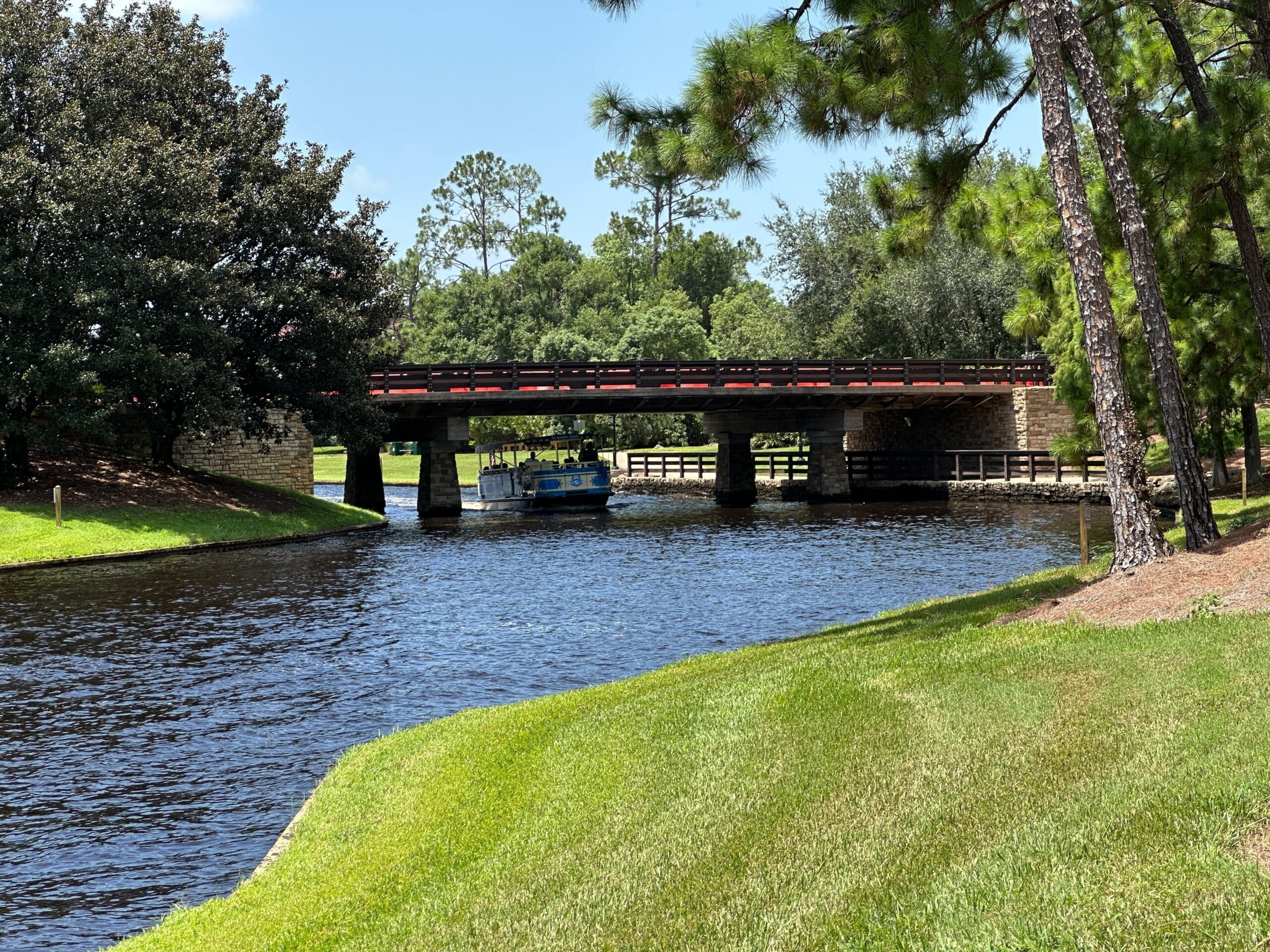 A small blue boat passes under a damaged bridge on a canal as the bridge reopens to traffic.
