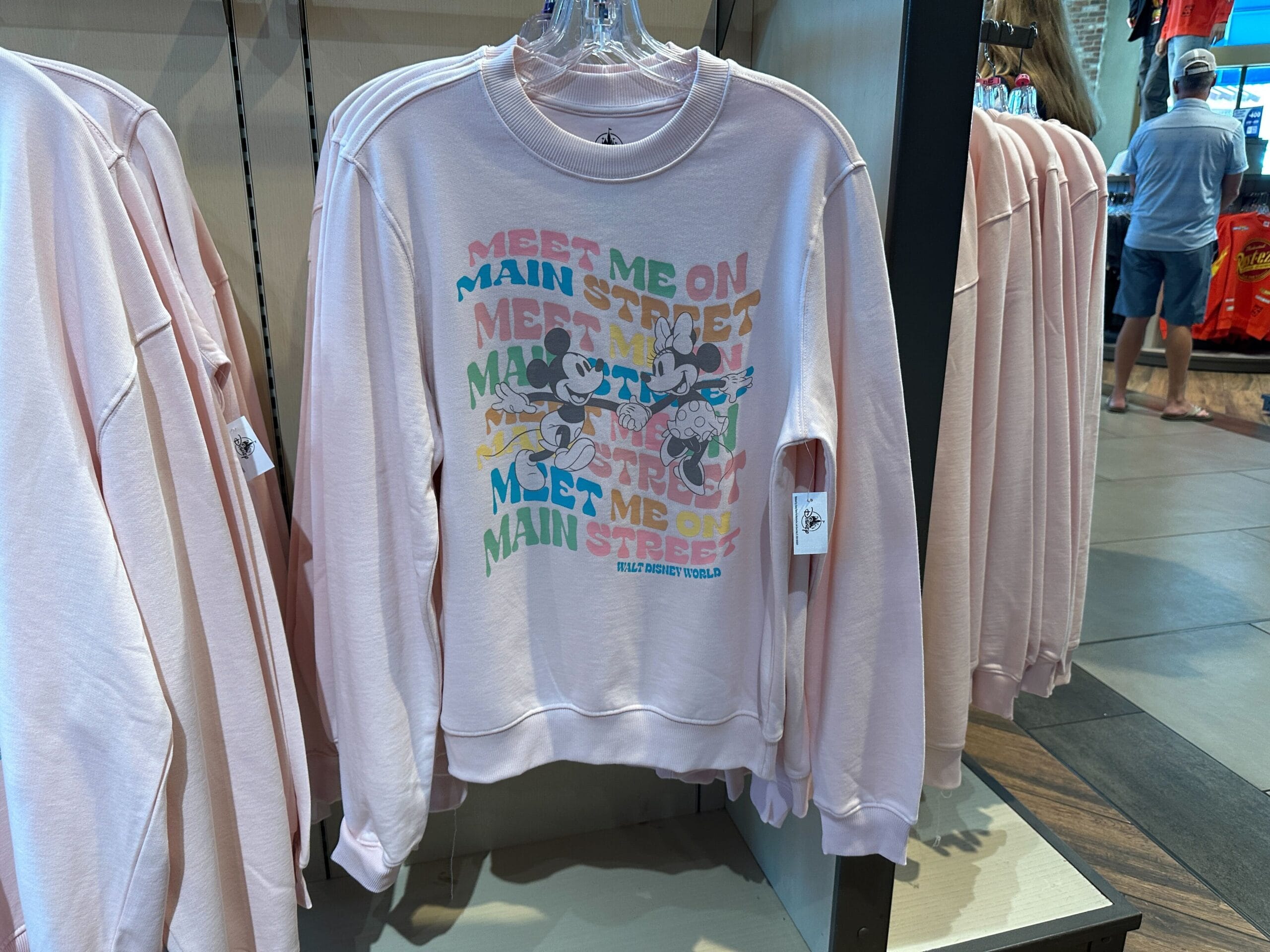 Light pink sweatshirt with Disney characters and “Meet Me on Main Street” text—charming new WDW branded merch.