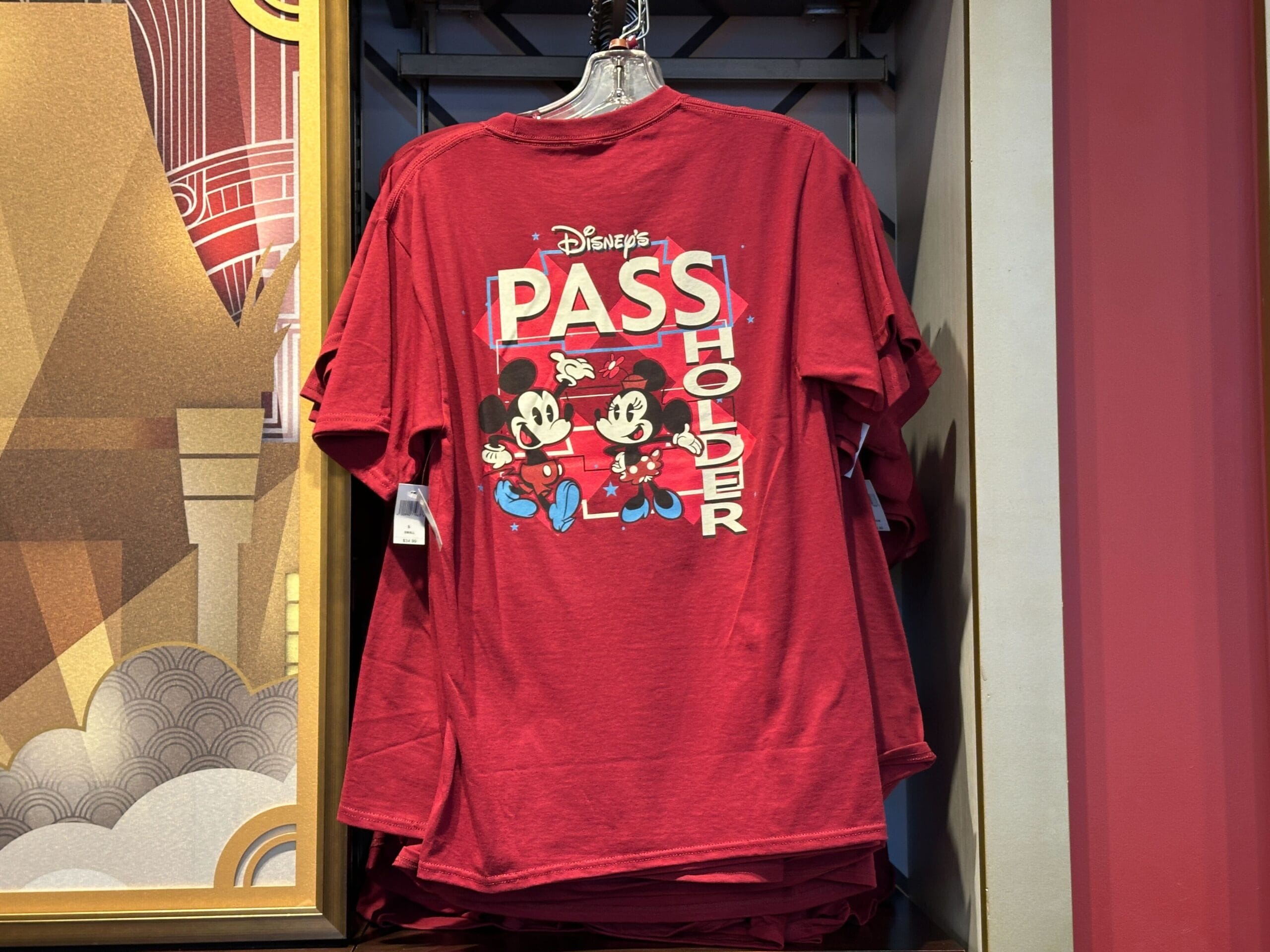 Red t-shirt with "Disney's Pass Holder" and Mickey & Minnie, a fun WDW Merch find hanging on a store rack.