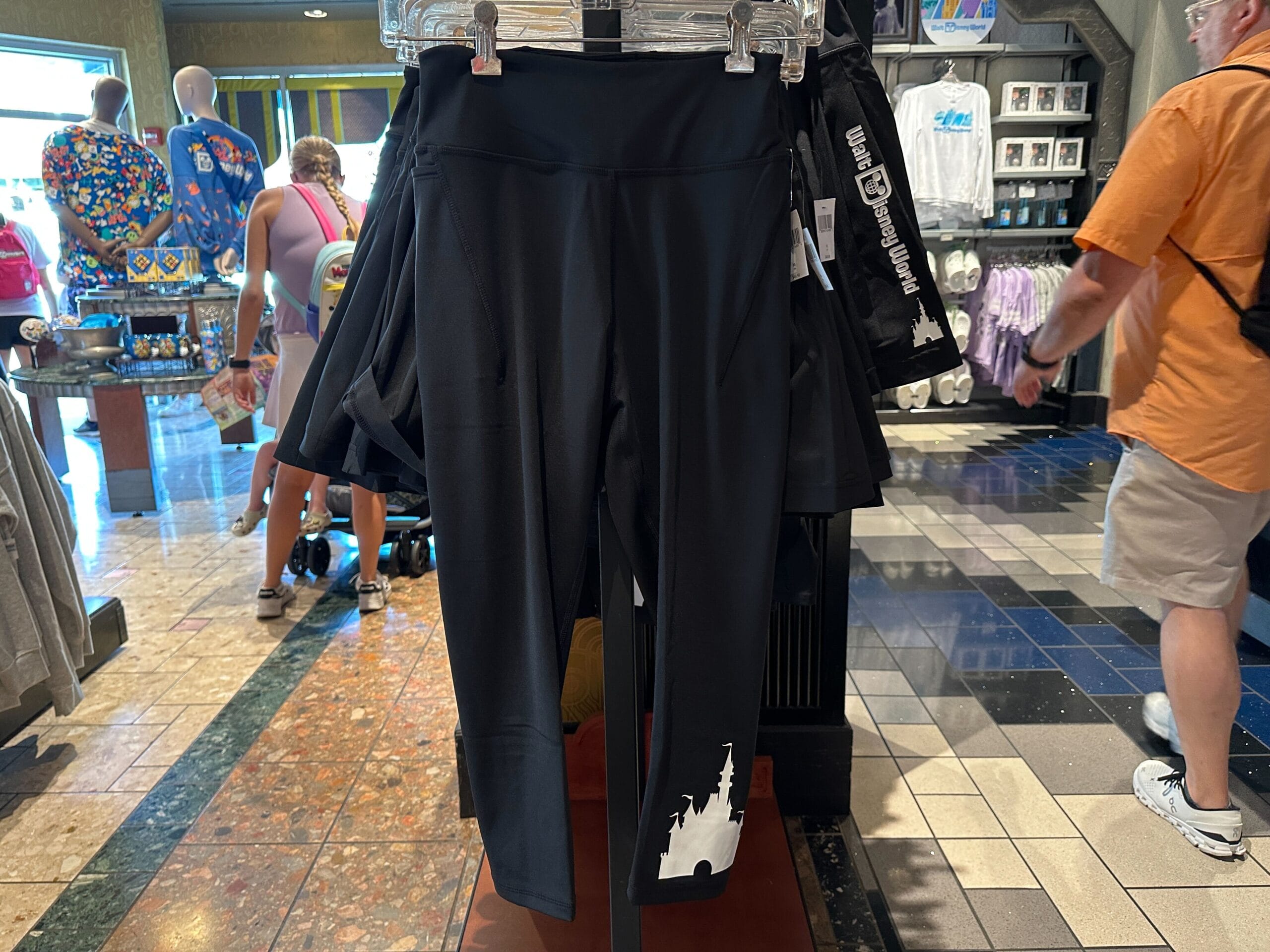 Black leggings with a white castle silhouette, part of the latest Disney merchandise, displayed on a store rack.