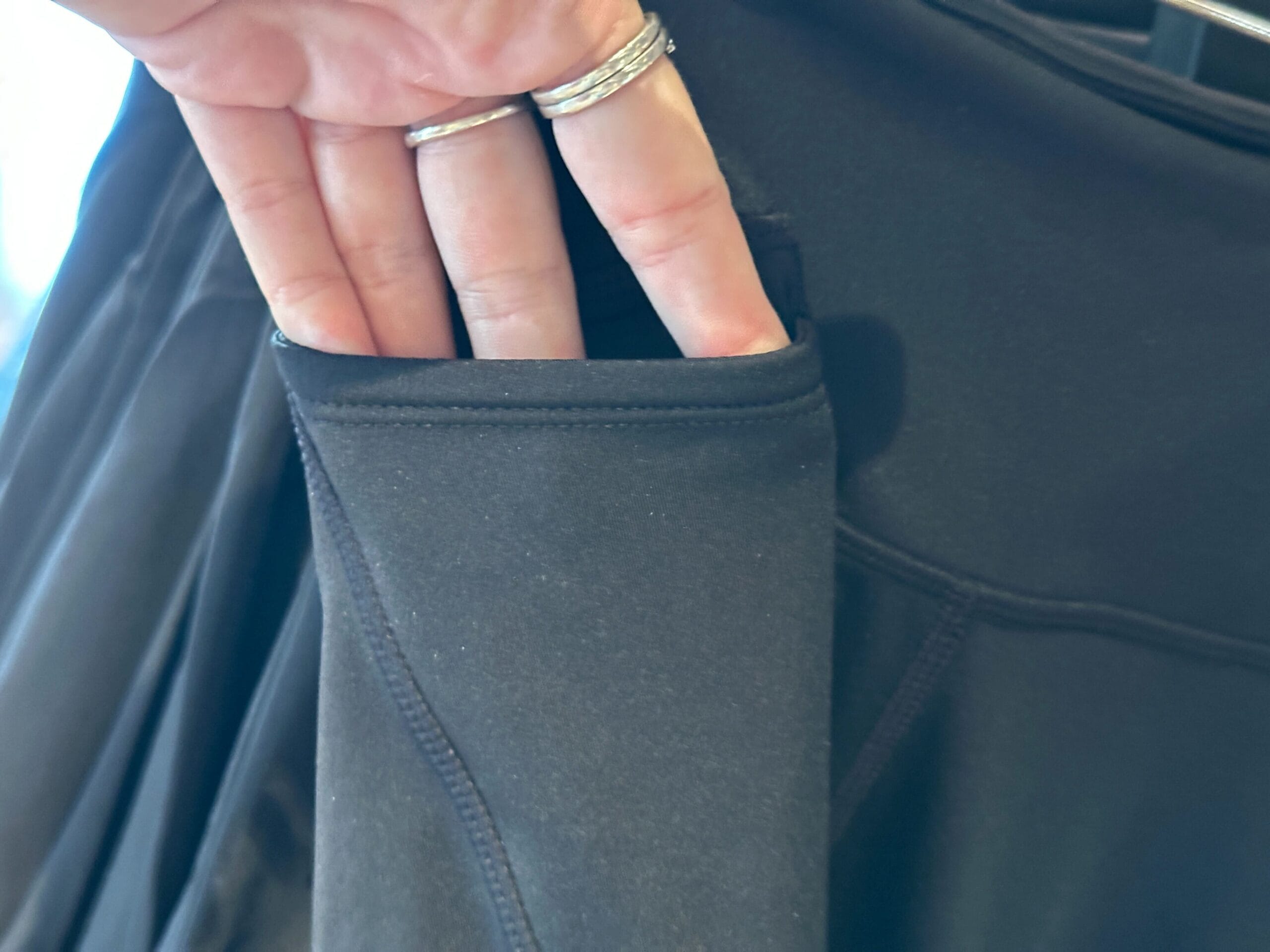 A hand with rings shows the side pocket of black athletic leggings, part of new Disney merchandise.