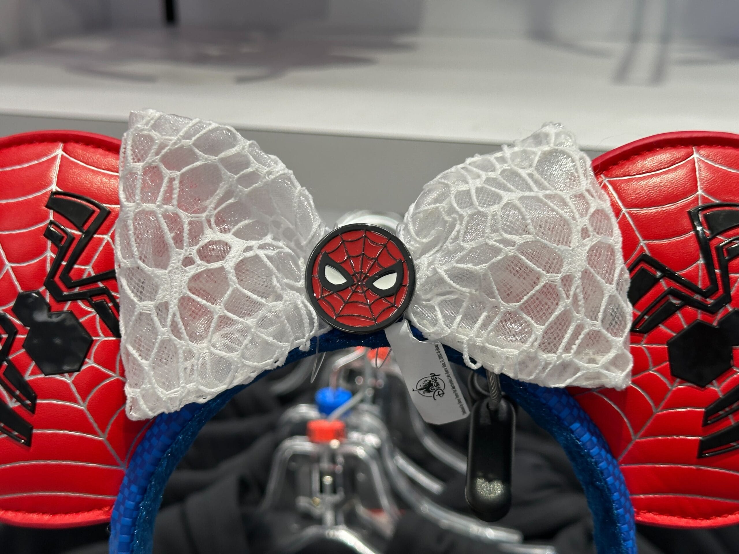 Red Spider-Man Mickey ears with a white lace bow, part of Marvel merchandise at Walt Disney World, displayed in-store.