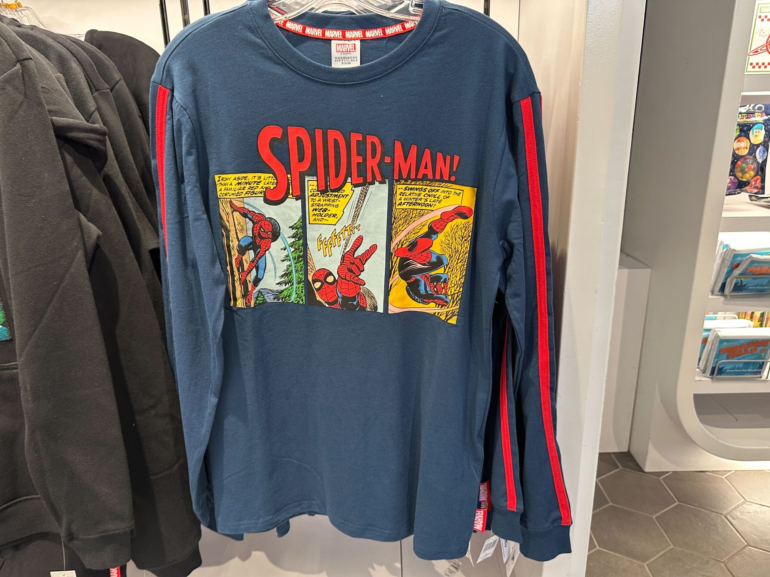 Blue long-sleeve shirt with red stripes and classic Spider-Man comic strip panels—official Marvel merchandise.