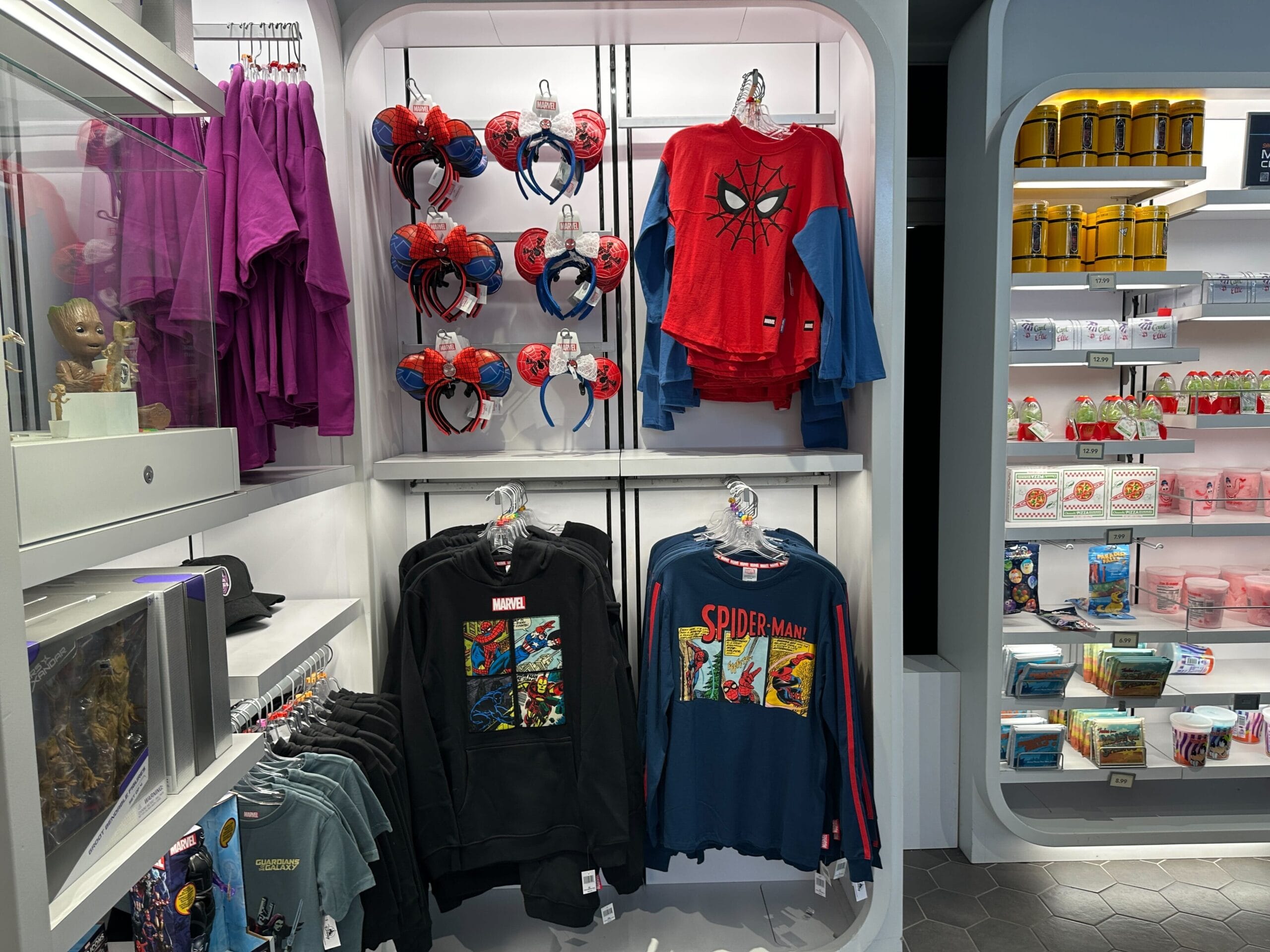 Display of Spider-Man shirts, Fantastic Four apparel, and Marvel merchandise in a brightly lit retail store.