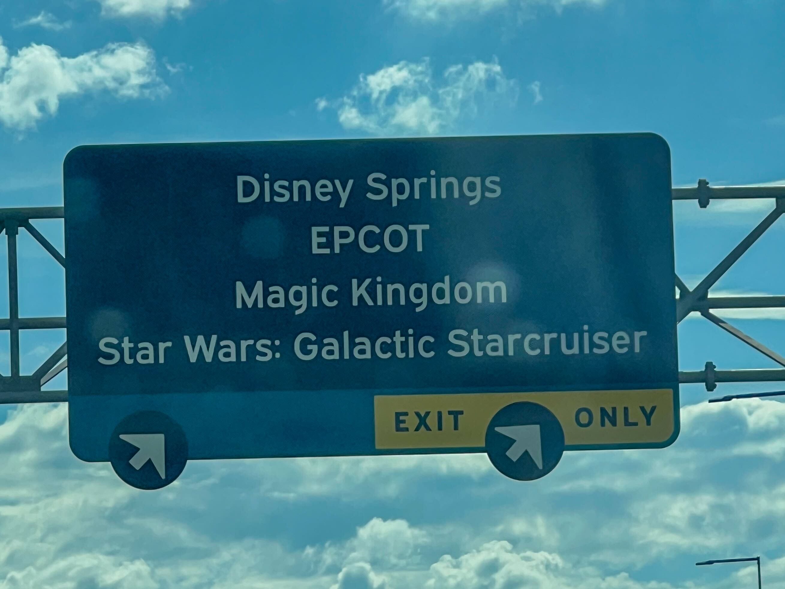 Highway sign listing Disney Springs, EPCOT, Magic Kingdom, and Star Wars: Galactic Starcruiser with exit arrows.