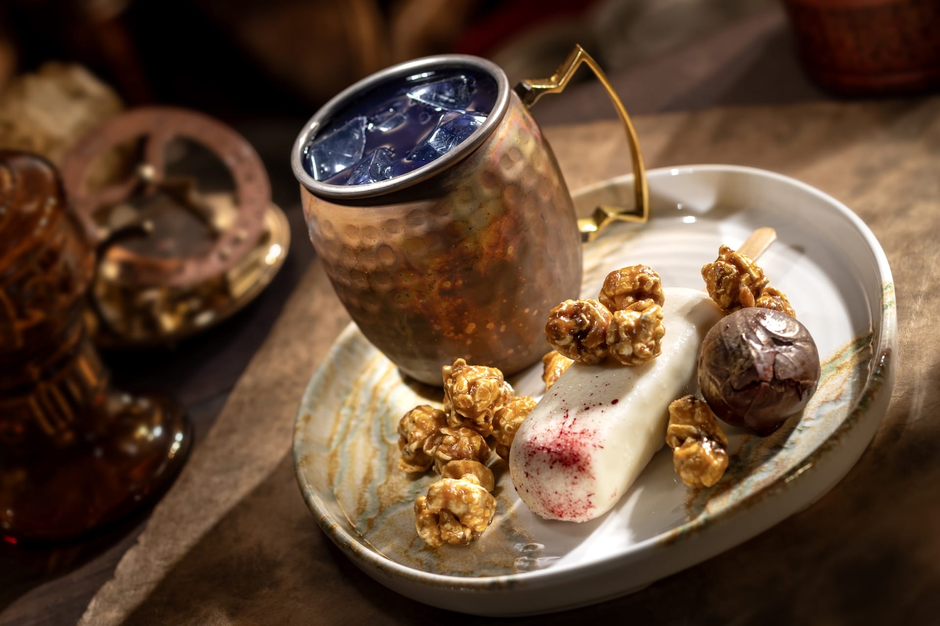 A first look: A copper mug with a dark iced drink beside treats from the Beak and Barrel Menu.