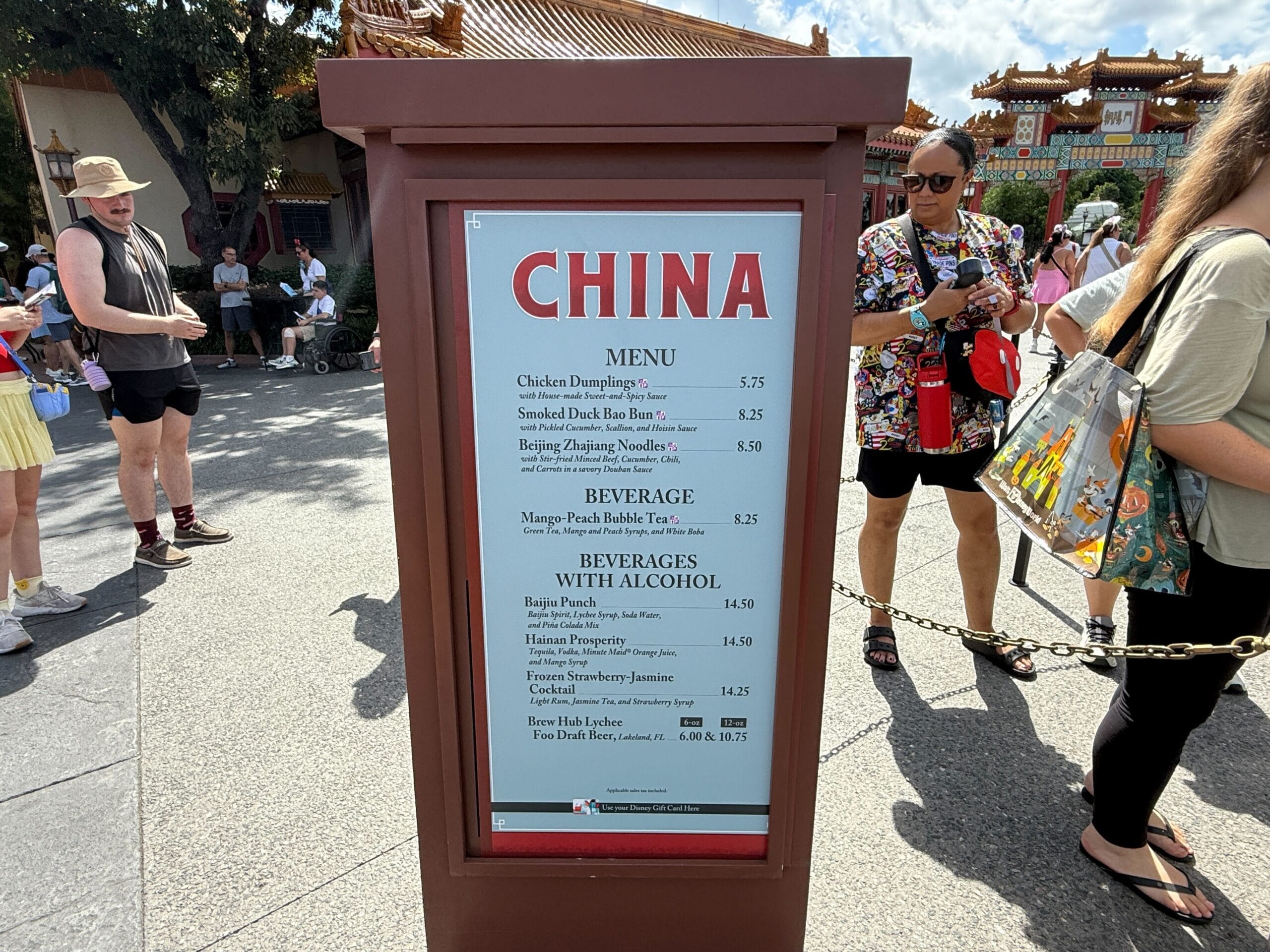 Menu sign for China food booth at a Food & Wine event, with people mingling and buildings in the background.