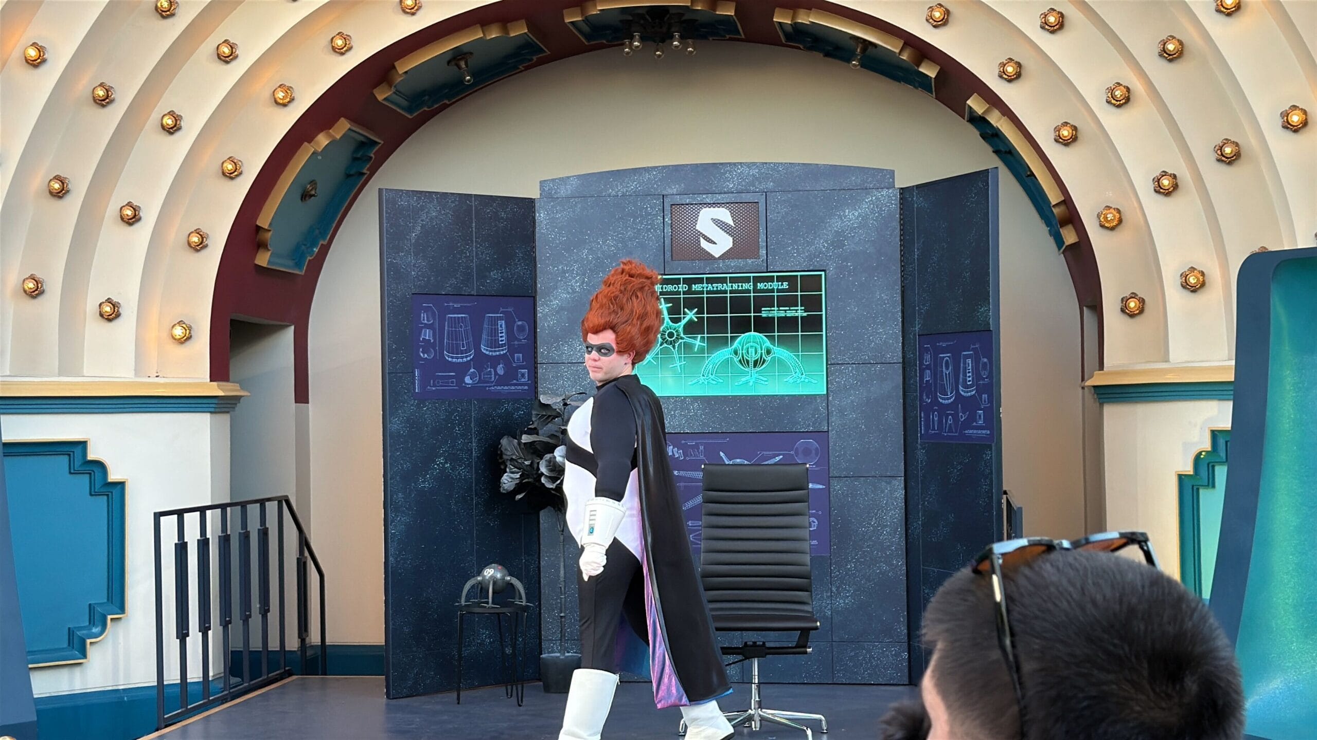 A person in a tall red wig performs on a Disney sci-fi stage, similar to Oogie Boogie Bash Treat Trail Locations.