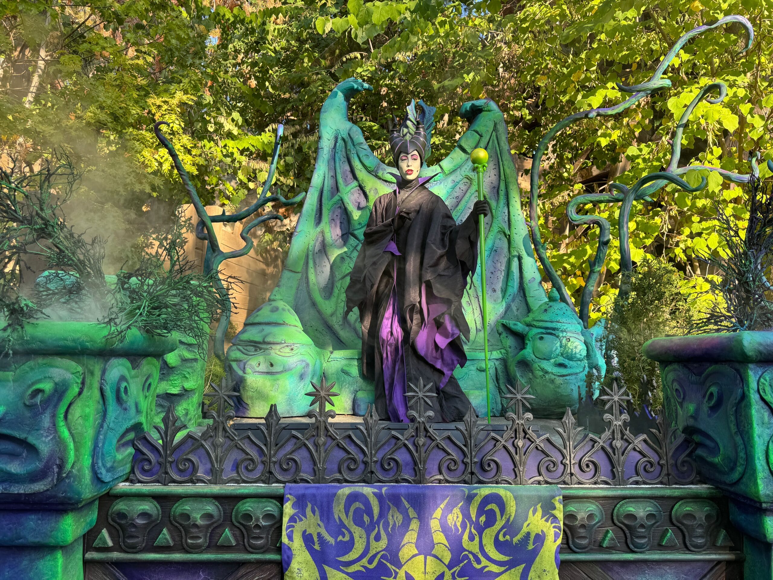 A person dressed as Maleficent stands on a colorful, Disney dragon-themed float at the Oogie Boogie Bash.