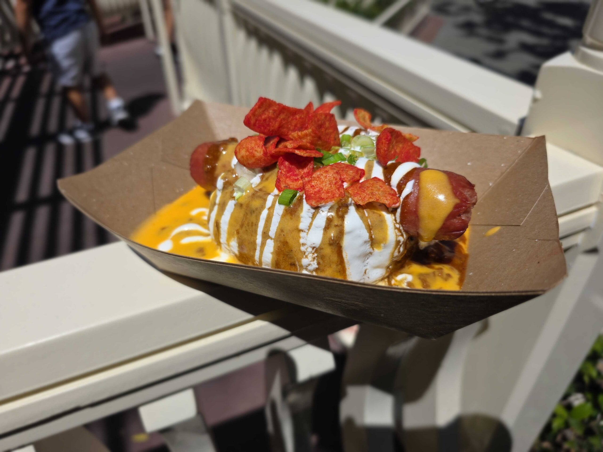 A Halloween chili cheese hot dog from Refreshment Corner, topped with sour cream, green onions, and red crunchy chips.