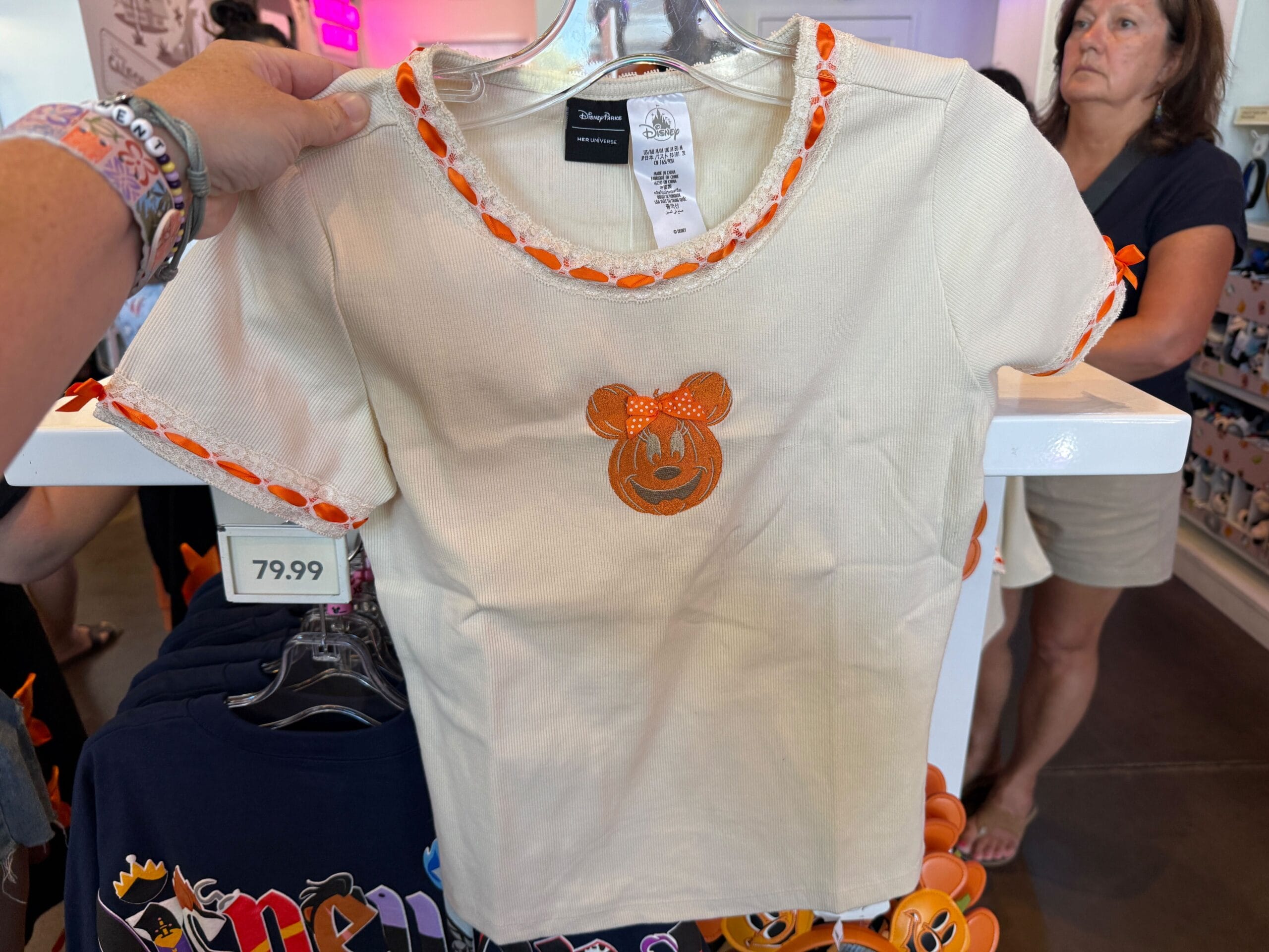 Cream T-shirt with an orange Minnie Mouse pumpkin design—perfect Pumpkin Merch. Price tag shows $79.99 in store.