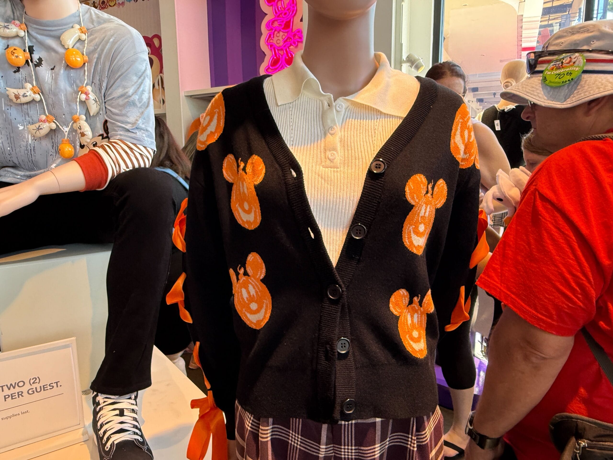 Mannequin wearing Pumpkin Apparel: a black cardigan with orange Mickey Mouse pumpkins, white shirt, and plaid skirt in-store.