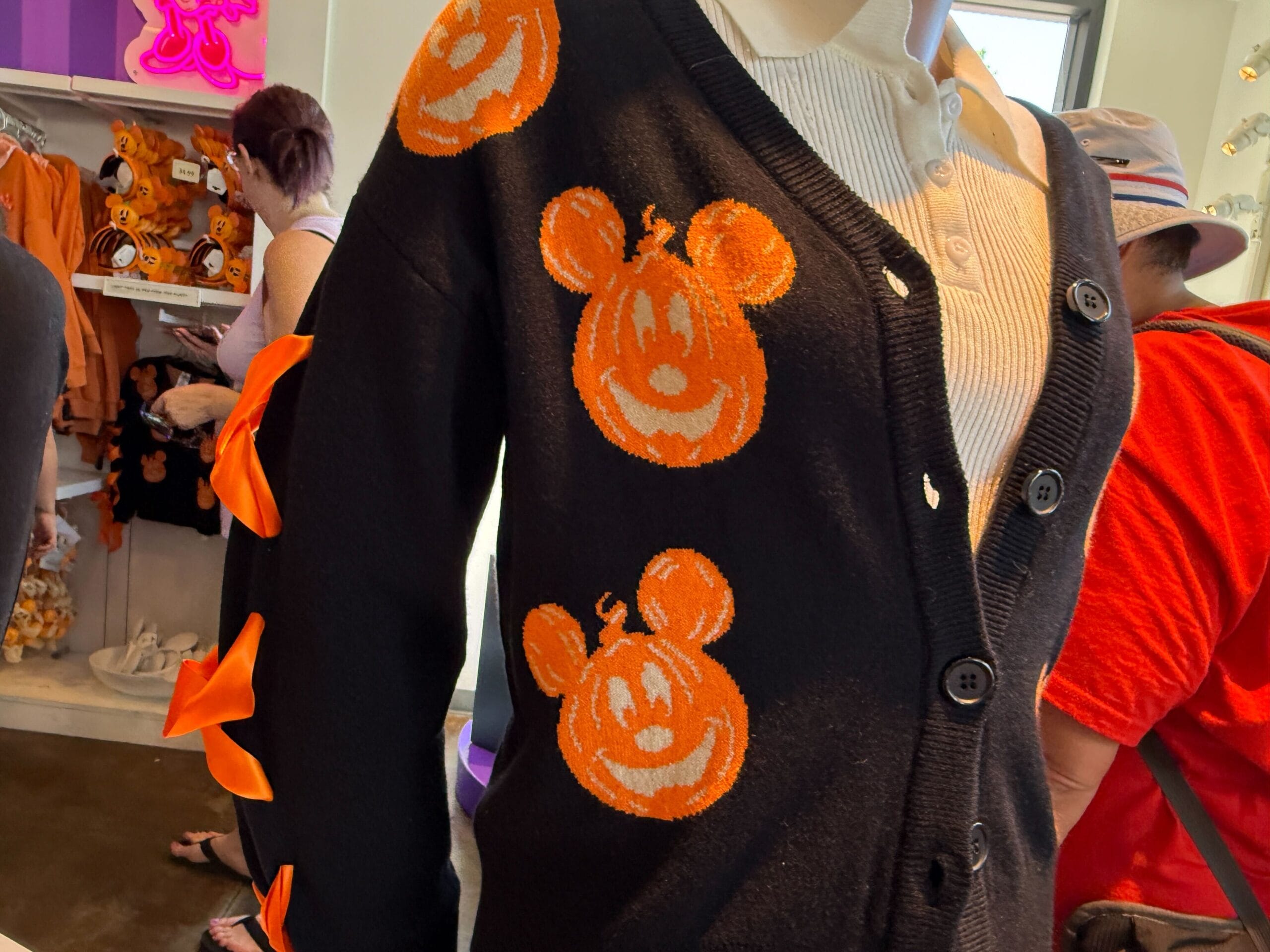 Black cardigan with orange Mickey Mouse pumpkin faces—perfect Pumpkin Apparel—plus orange ribbon bows on the sleeves.