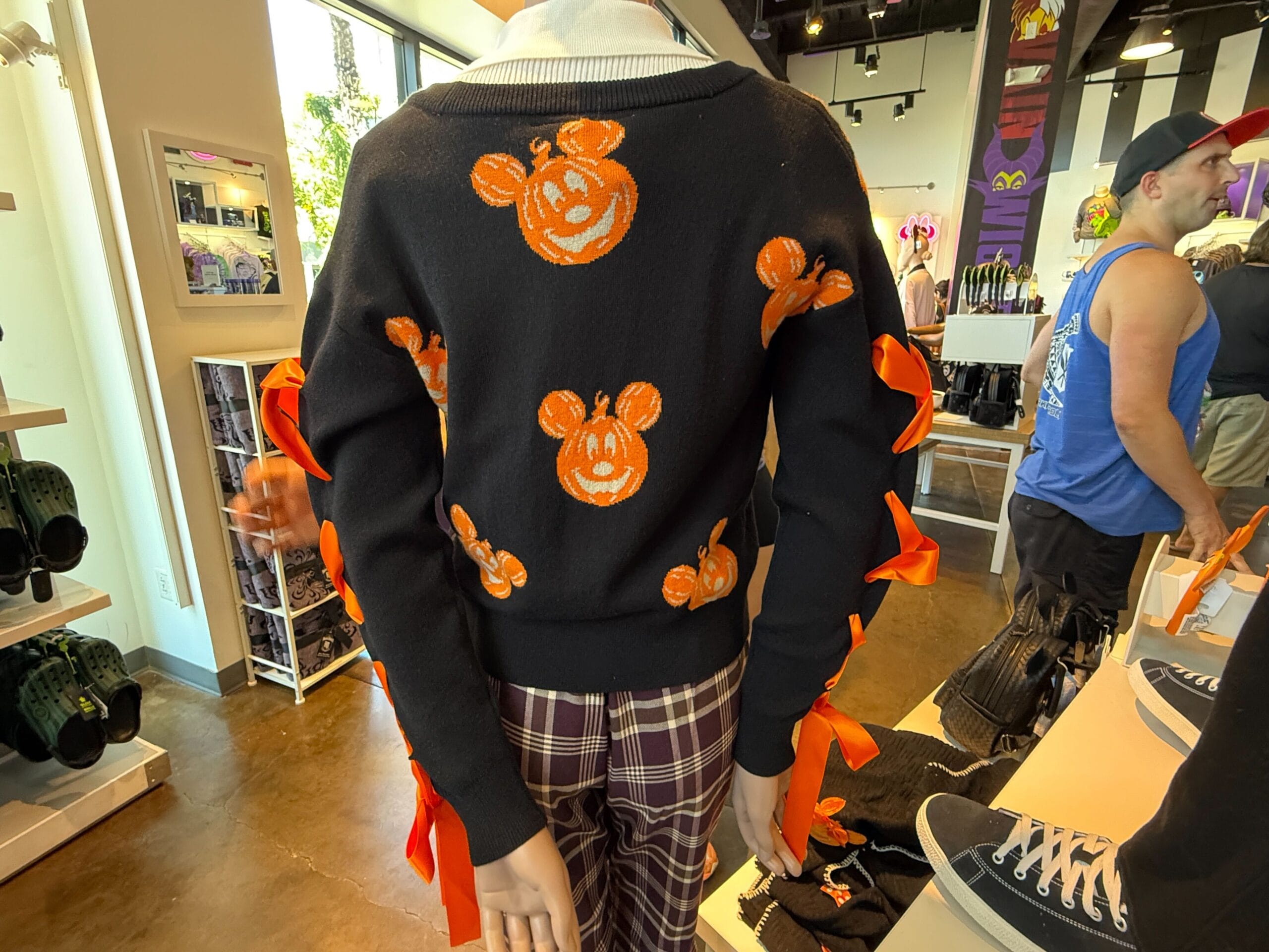A mannequin wears Pumpkin Apparel: a black sweater with orange Mickey Mouse pumpkin faces and ribbon bows on the sleeves.