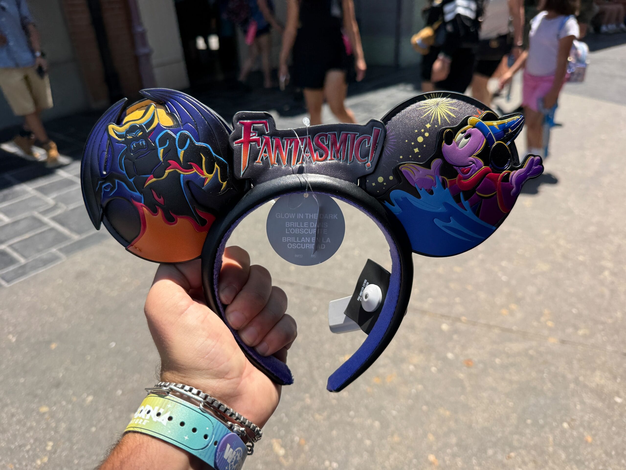 A person holds a Fantasmic Ear Headband featuring Maleficent and Sorcerer Mickey designs at Disneyland Resort.