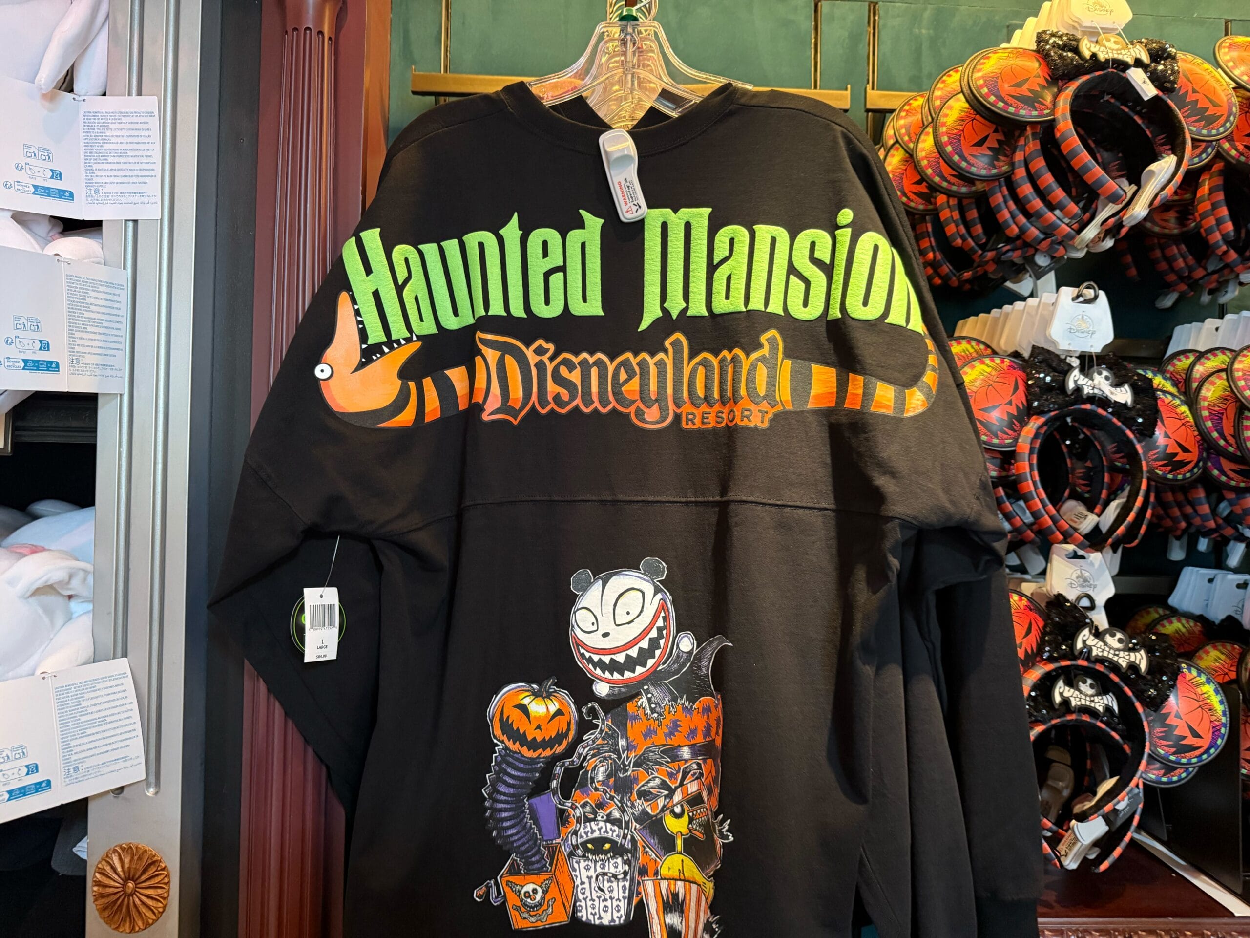 Black Haunted Mansion shirt with neon green and orange text, featuring spooky cartoon characters below.