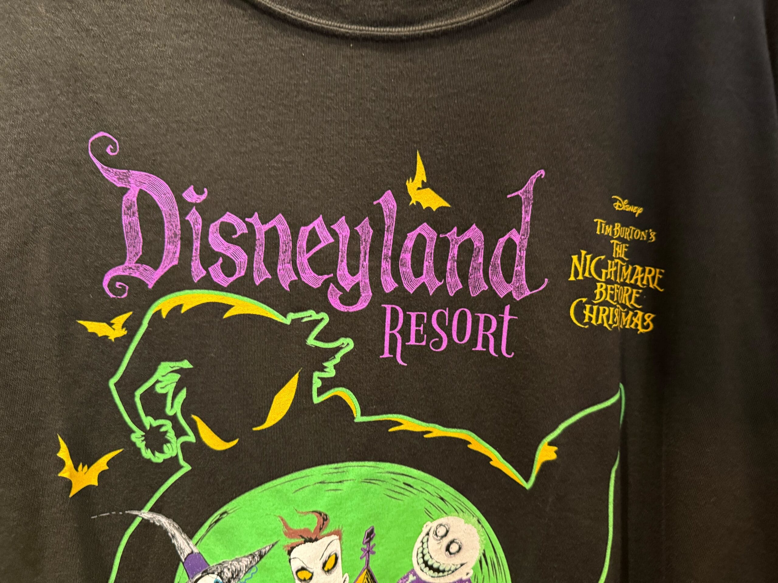 Black t-shirt with "Disneyland Resort" and "The Nightmare Before Christmas" Haunted Mansion Holiday graphics in vibrant colors.
