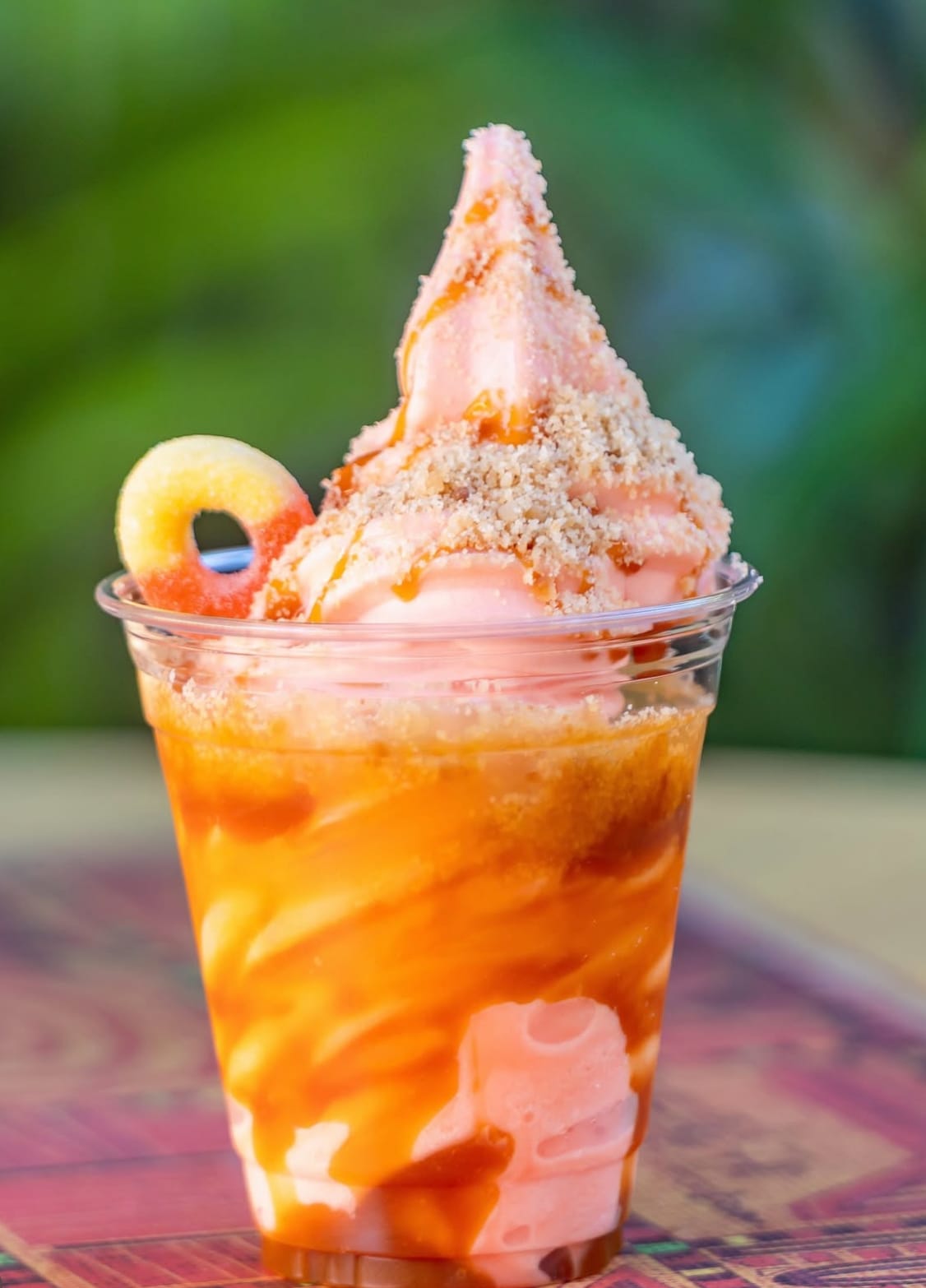 A Peach Sundae with swirled DOLE Whip, caramel sauce, cookie crumbs, and a gummy ring candy on top.