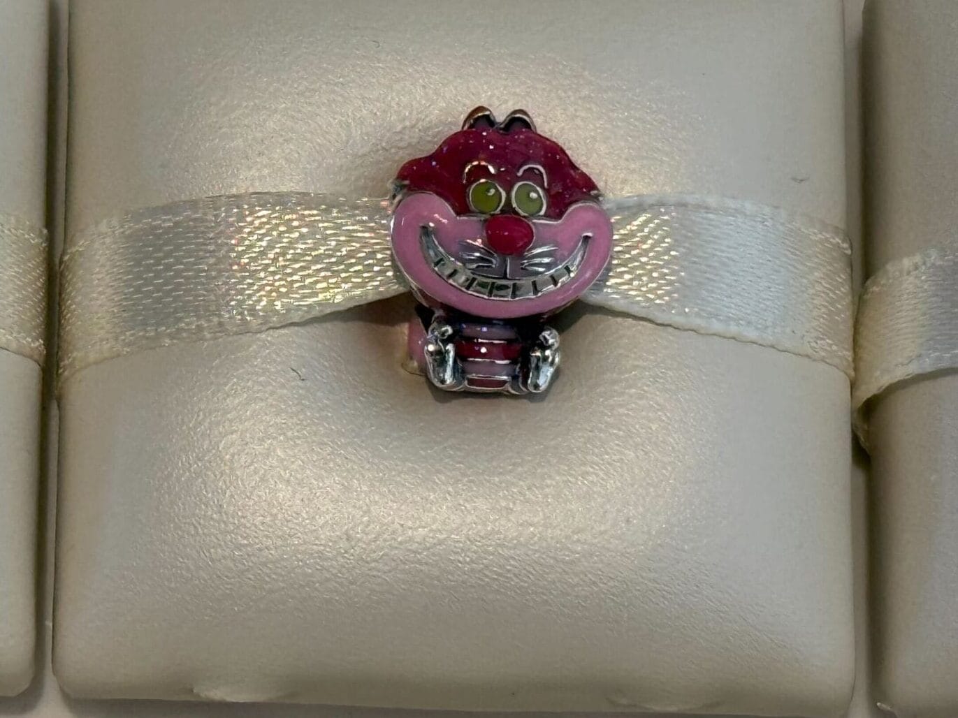 Two small Pandora Charms of Dumbo and the Cheshire Cat, displayed on cushioned holders. New from Disneyland Resort.