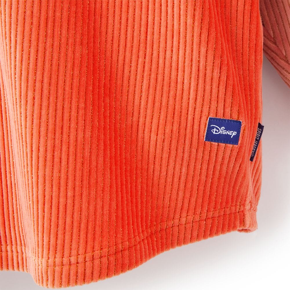 Close-up of an orange corduroy fabric from the Pumpkin Spice Collection with a blue Disney Store tag near the hem.