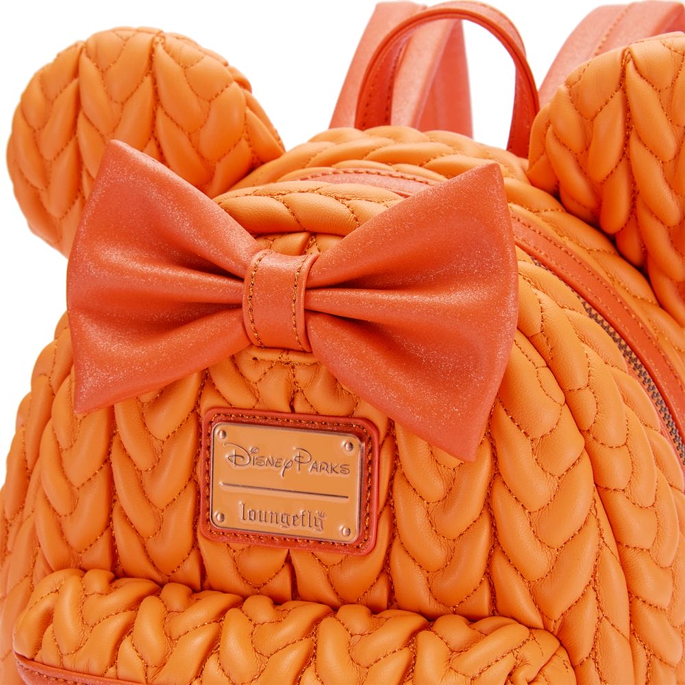 Close-up of an orange backpack with mouse ears and a bow, perfect for fall, featuring a Disney Parks Loungefly metal label.
