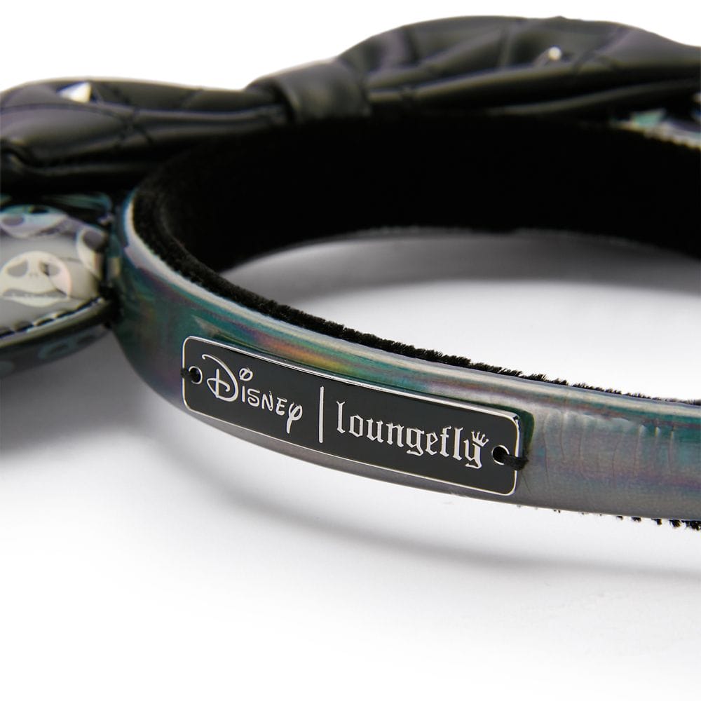 Close-up of a Disney x Loungefly headband featuring a metal logo plate and part of black bow and ears.