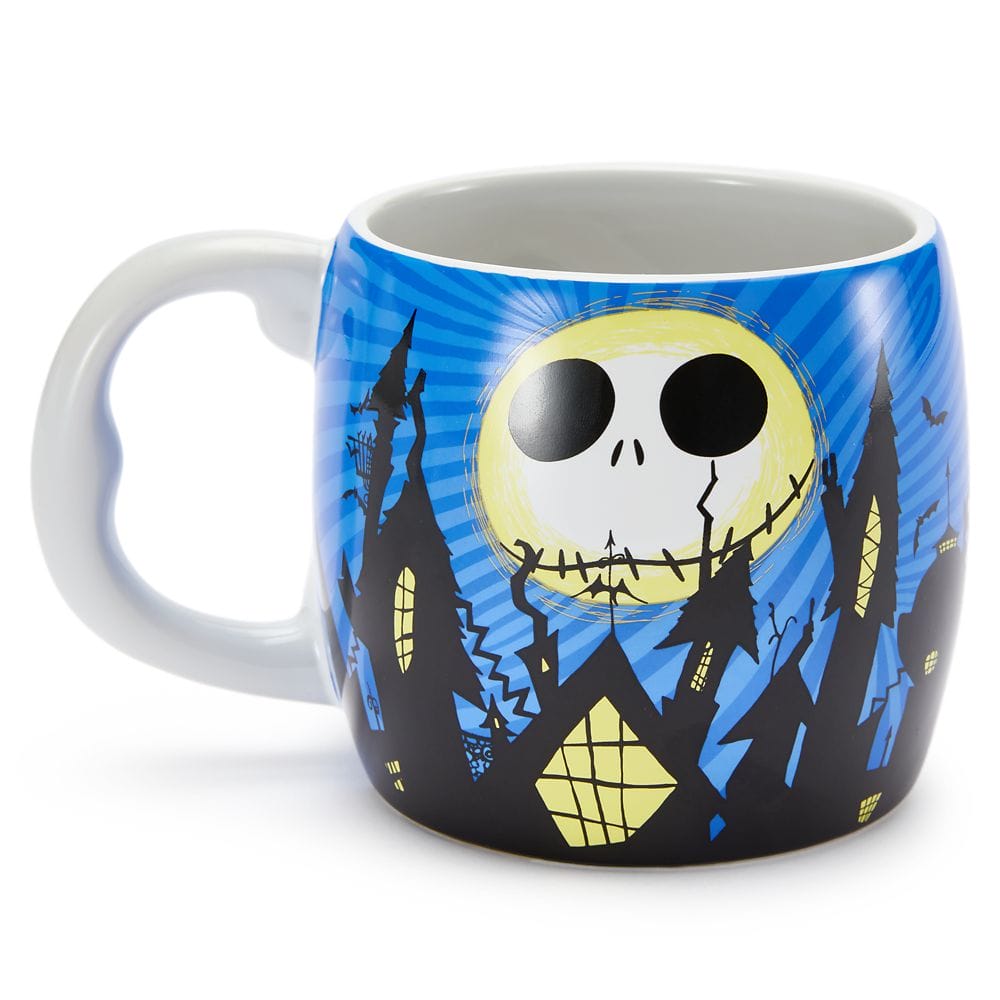 A mug with a design of a large yellow moon with a skull face over spooky rooftops and a blue night sky.