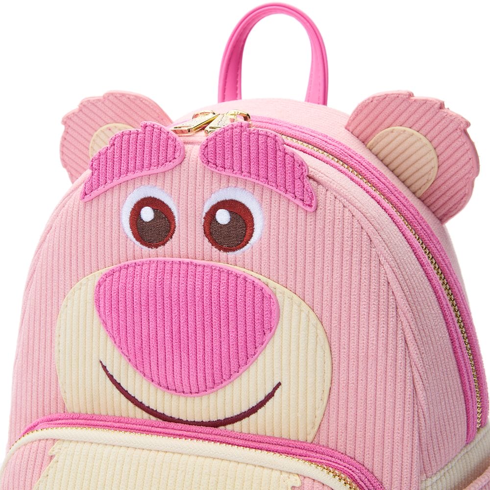 Pink backpack with a smiling bear face design, featuring a zipper and a handle at the top.