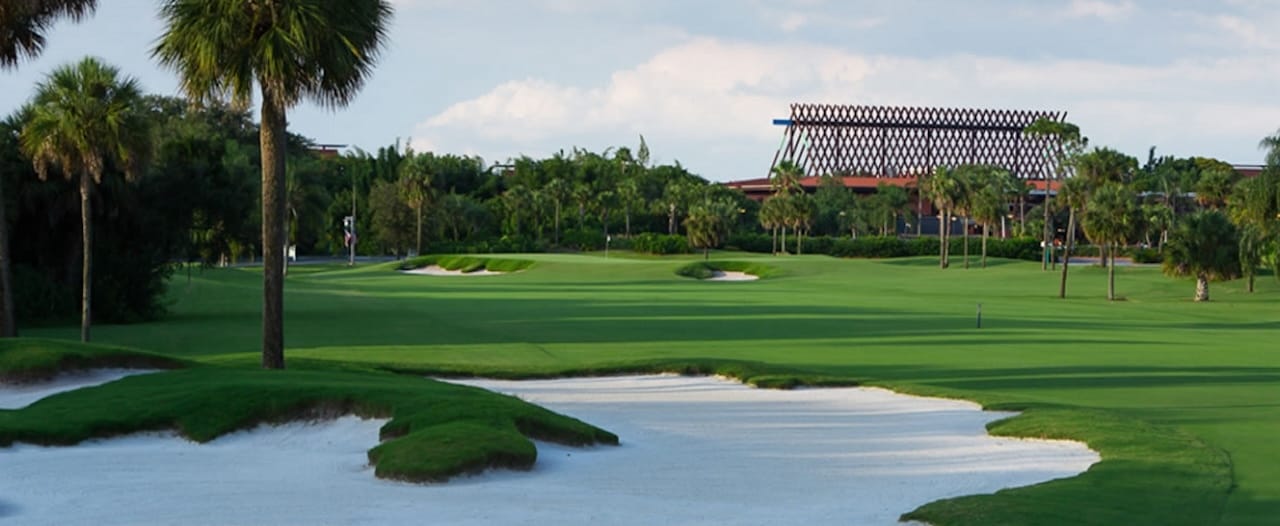 Enjoy Disney's Palm Golf Course, with sand bunkers and palm trees near Walt Disney World, under a partly cloudy sky.