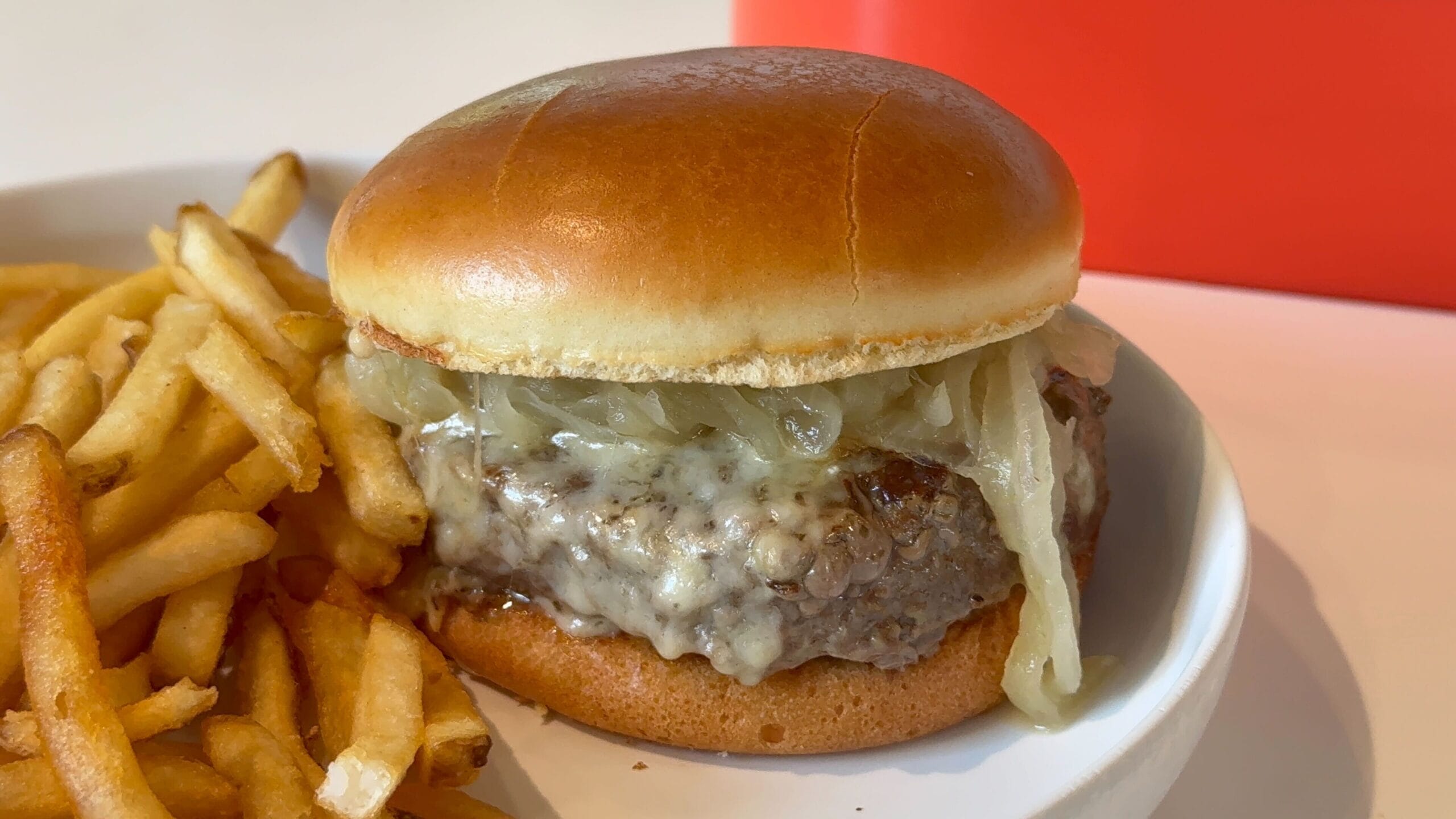 New Food & Wine: Cheeseburger with melted cheese and onions, served with crispy fries on a white plate.
