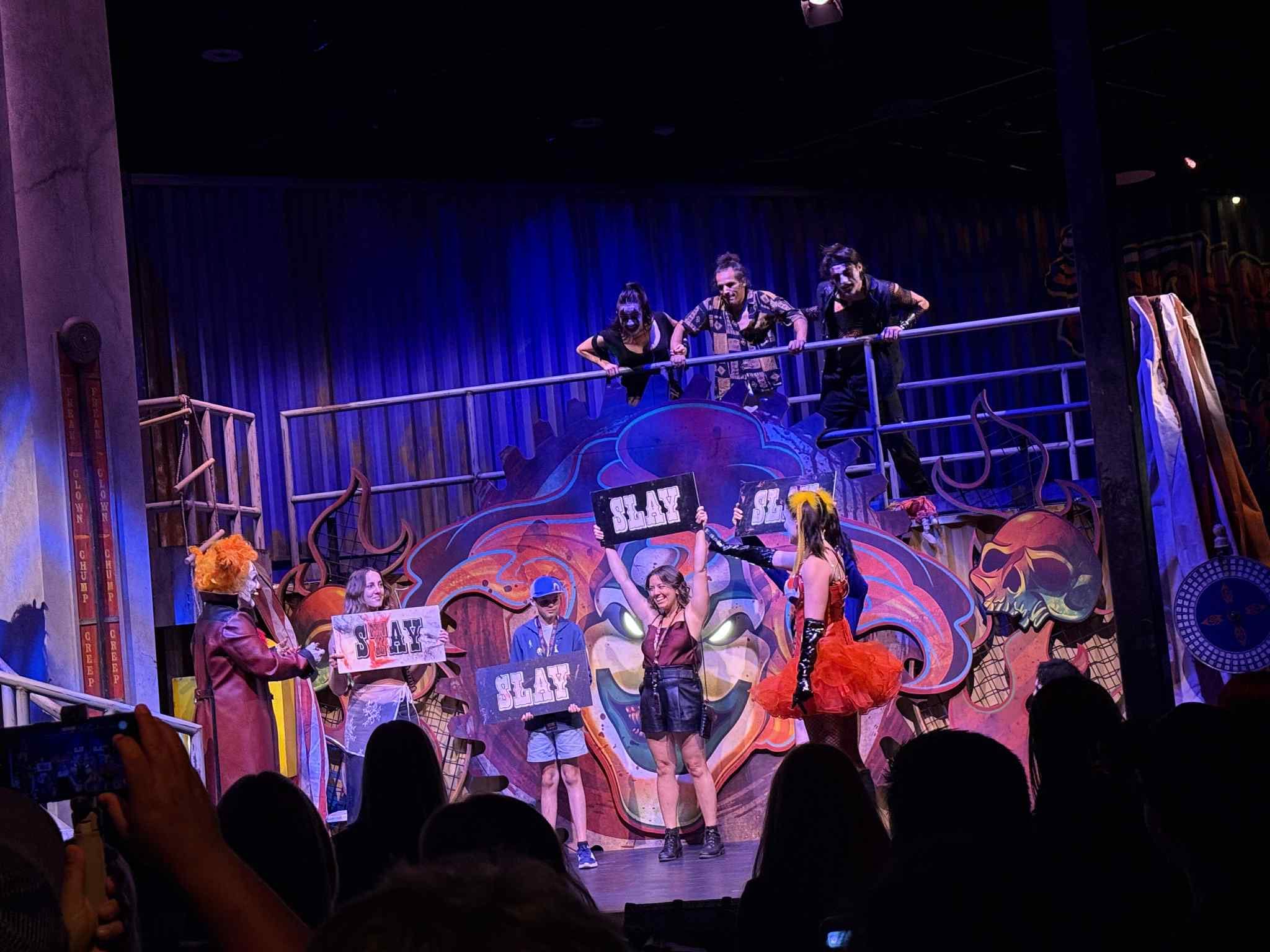 Performers in colorful costumes and makeup stand on stage with children at Universal Horror Unleashed Las Vegas.